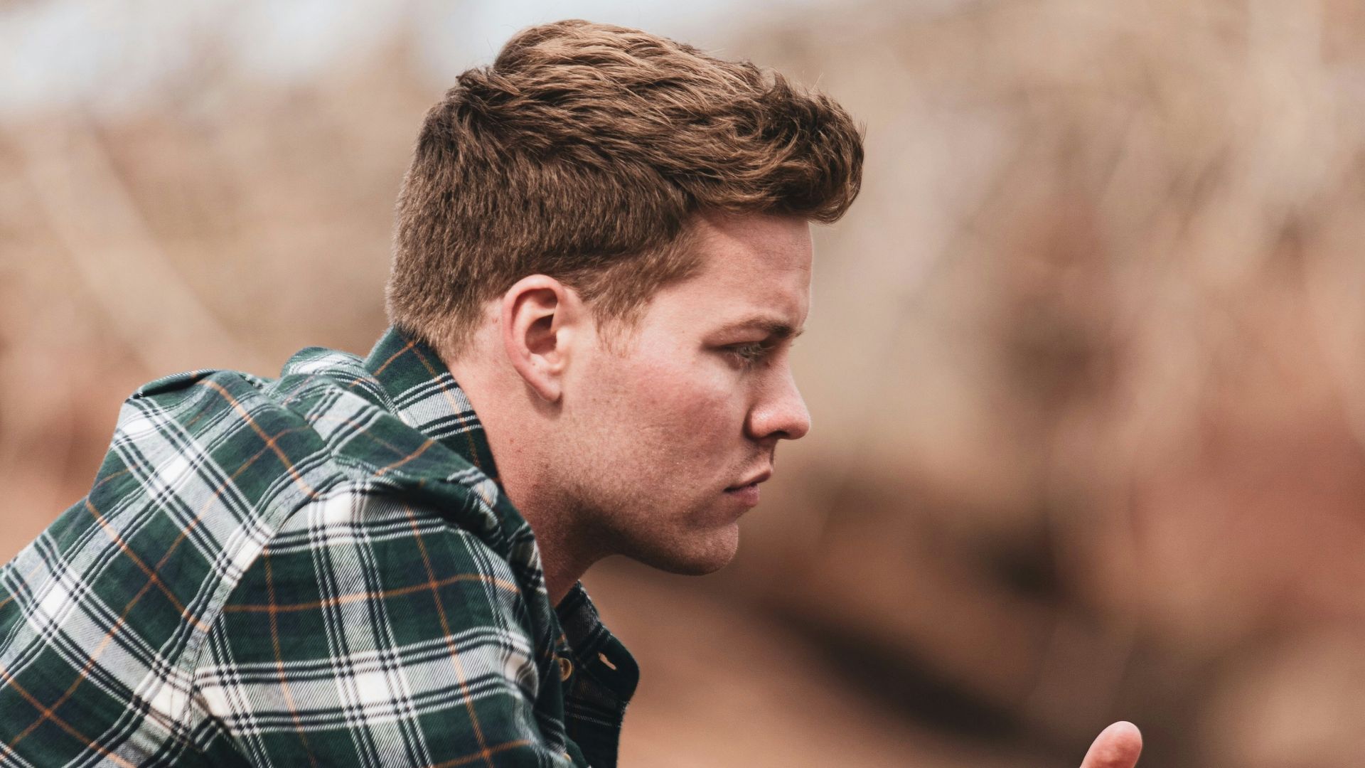 man in black white and gray plaid dress shirt holding smartphone