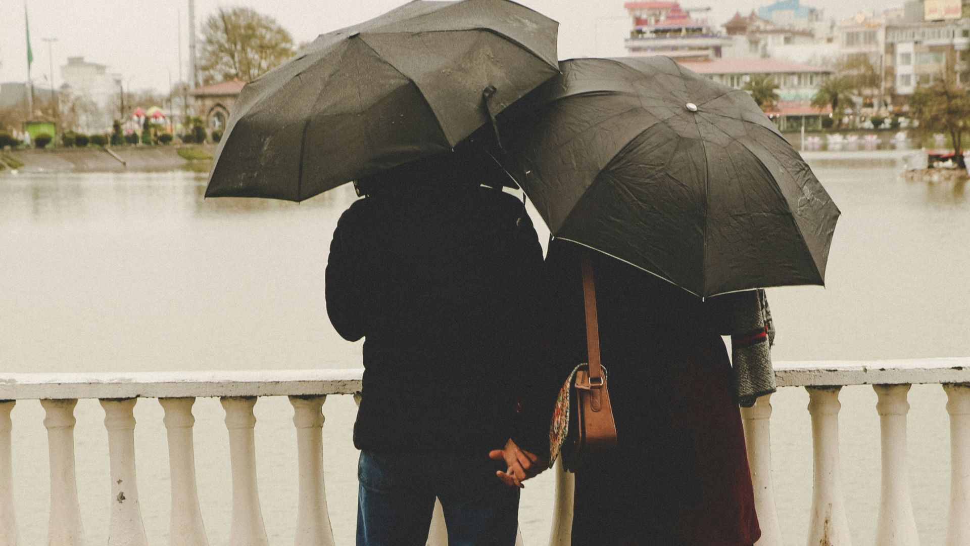 man and woman holding black umbrellas