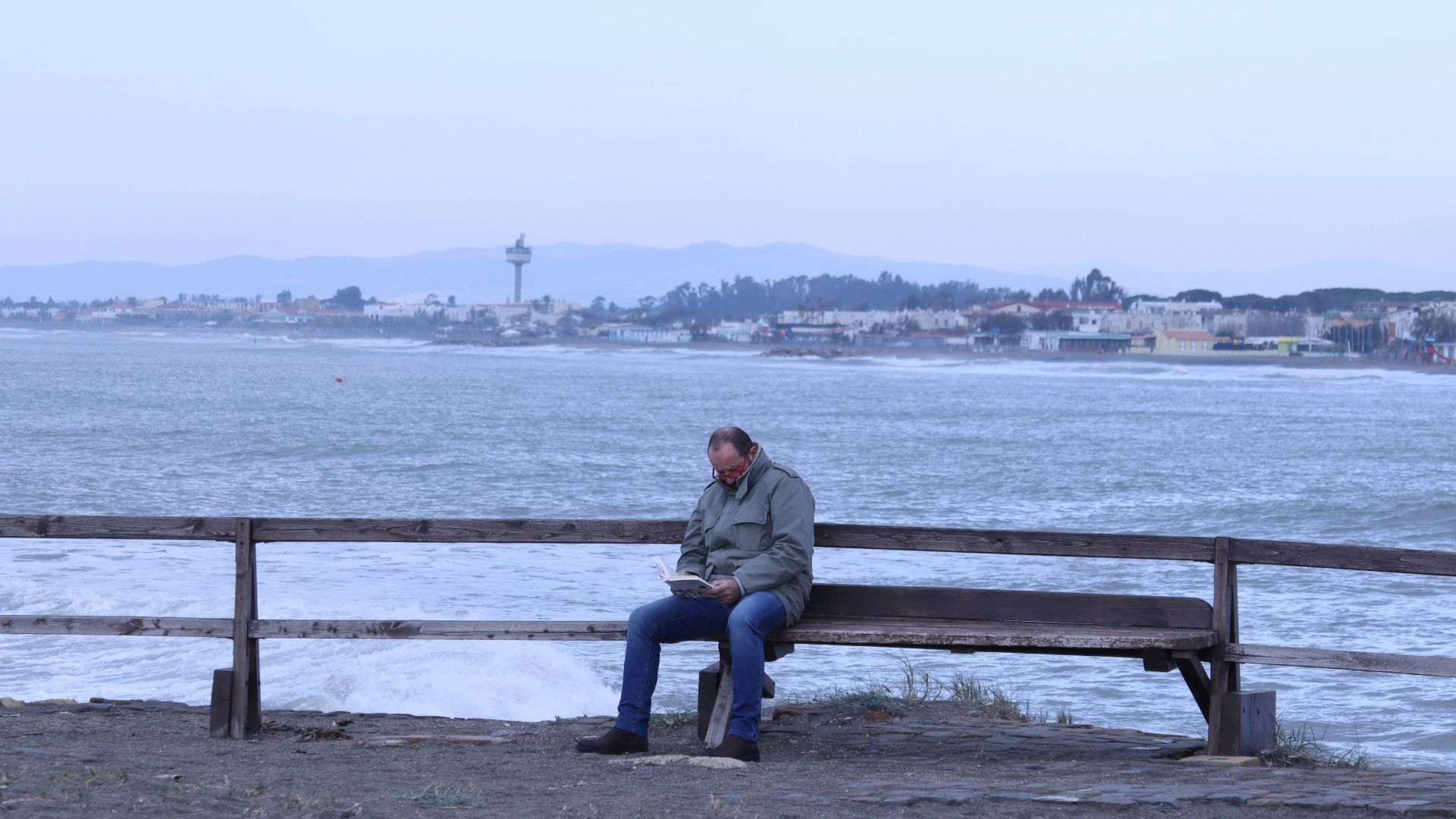 man and woman sitting on bench near body of water during daytime