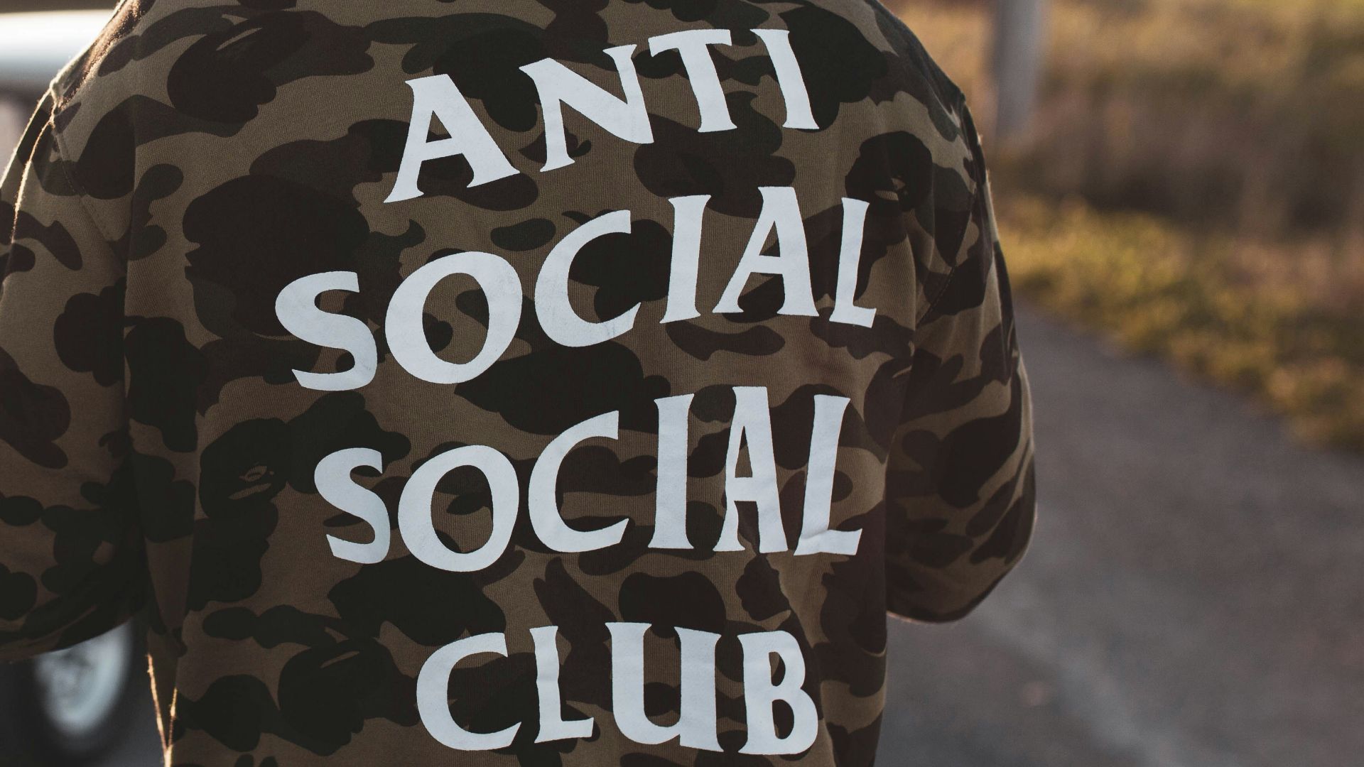 person in black and white hoodie standing on road during daytime
