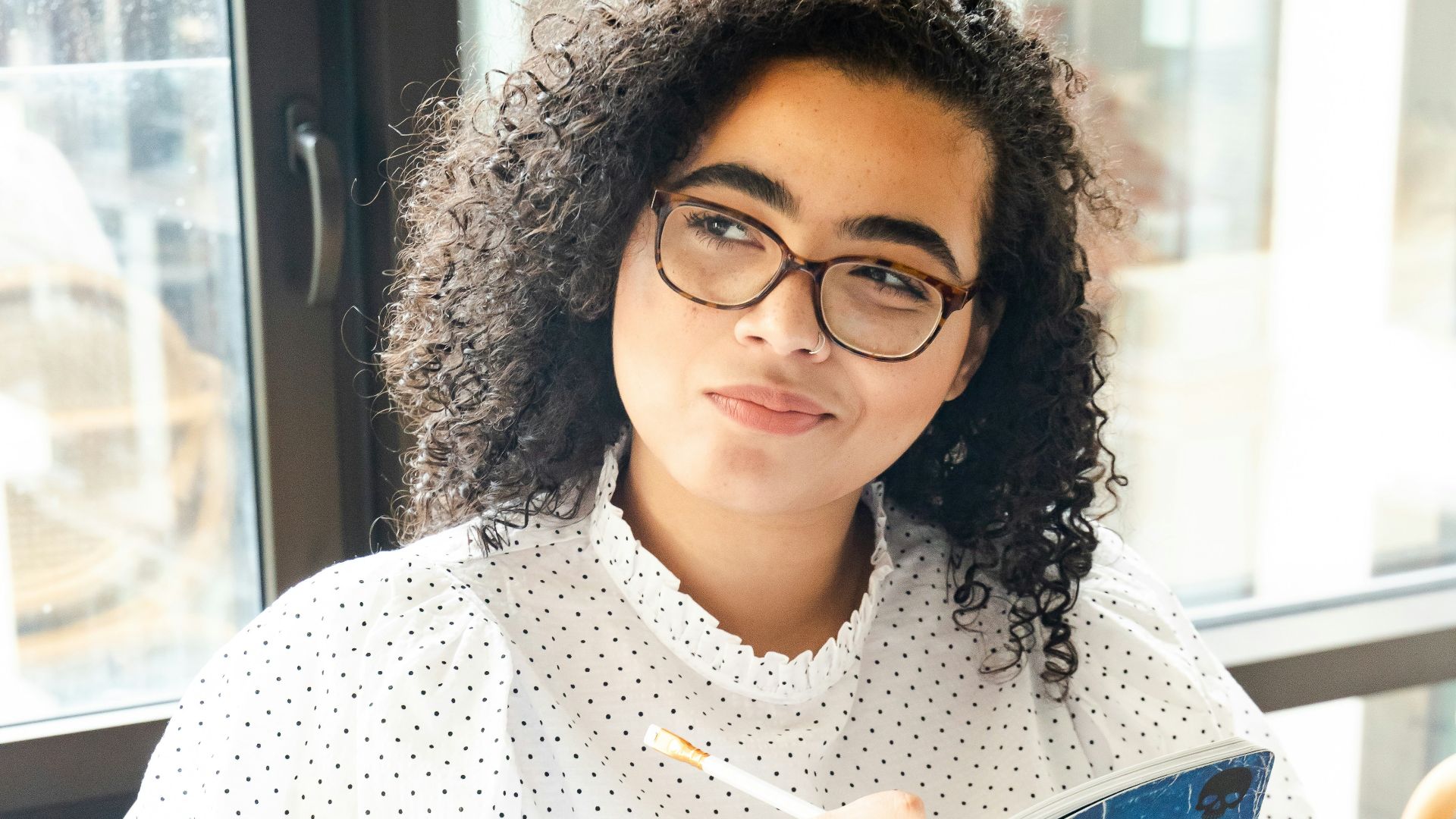 woman in white and black polka dot shirt holding blue and white book