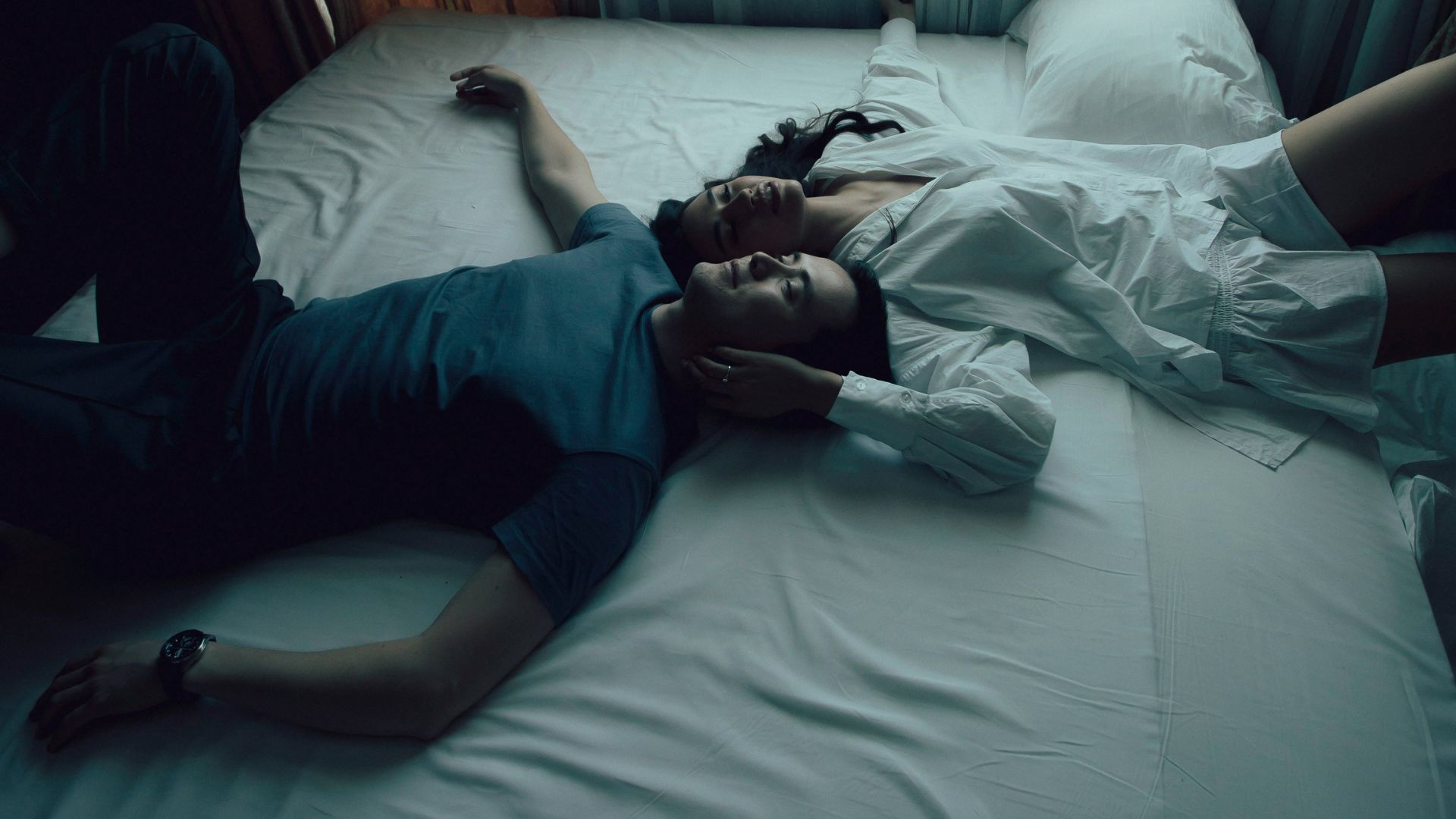 man in blue shirt lying on bed