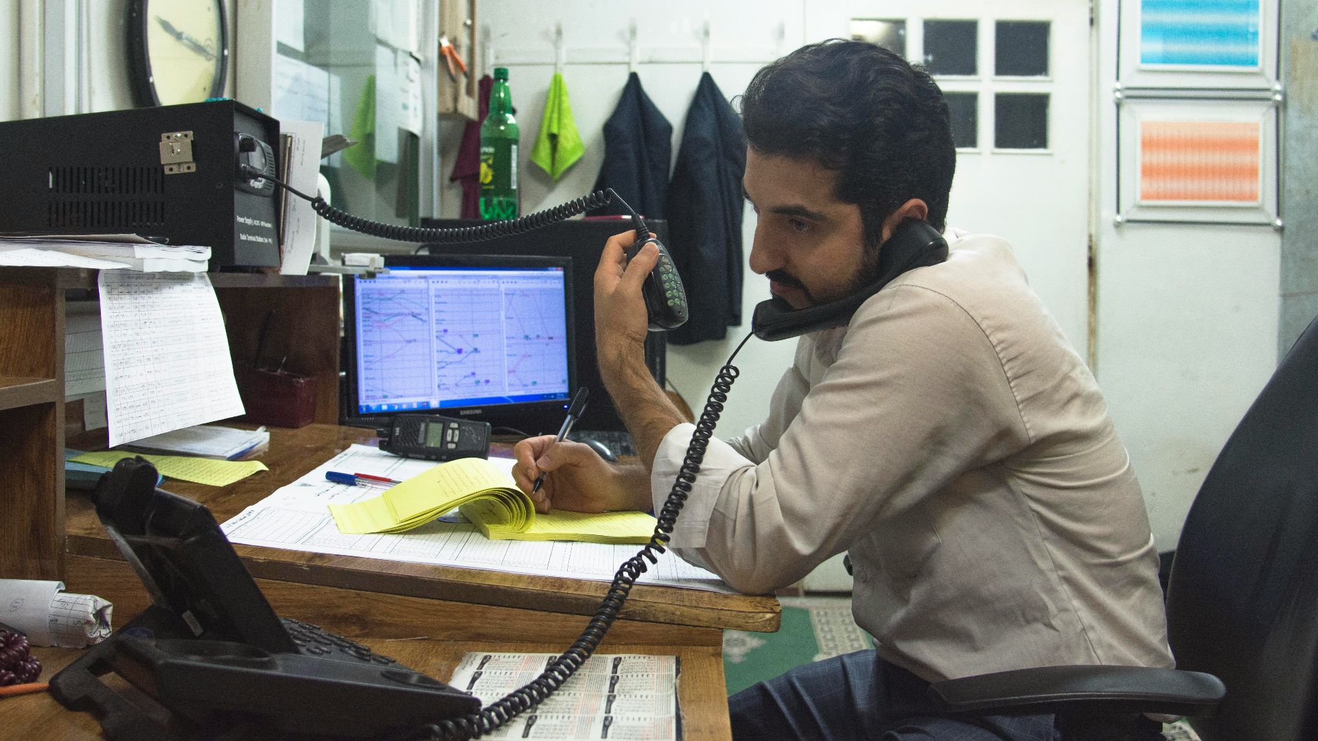 a man sitting at a desk talking on a phone