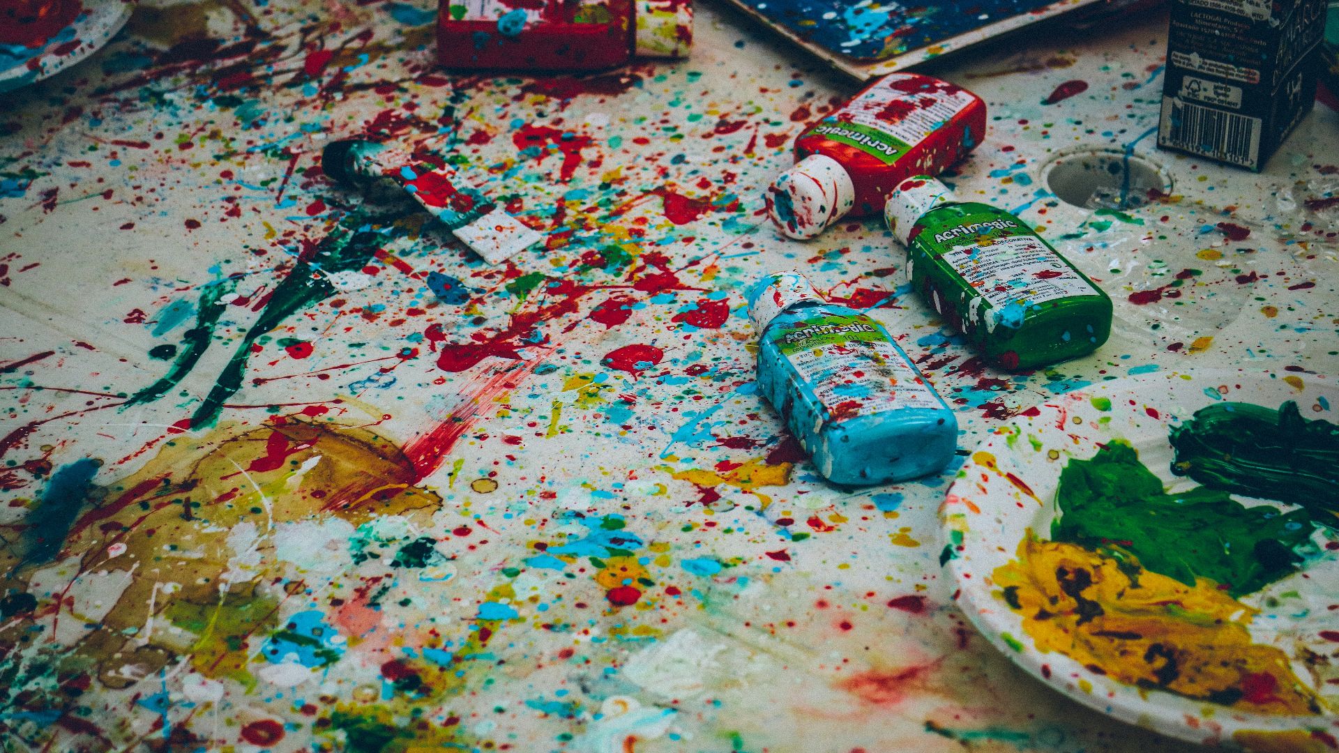 assorted-color bottles on white surface with paint scribbles