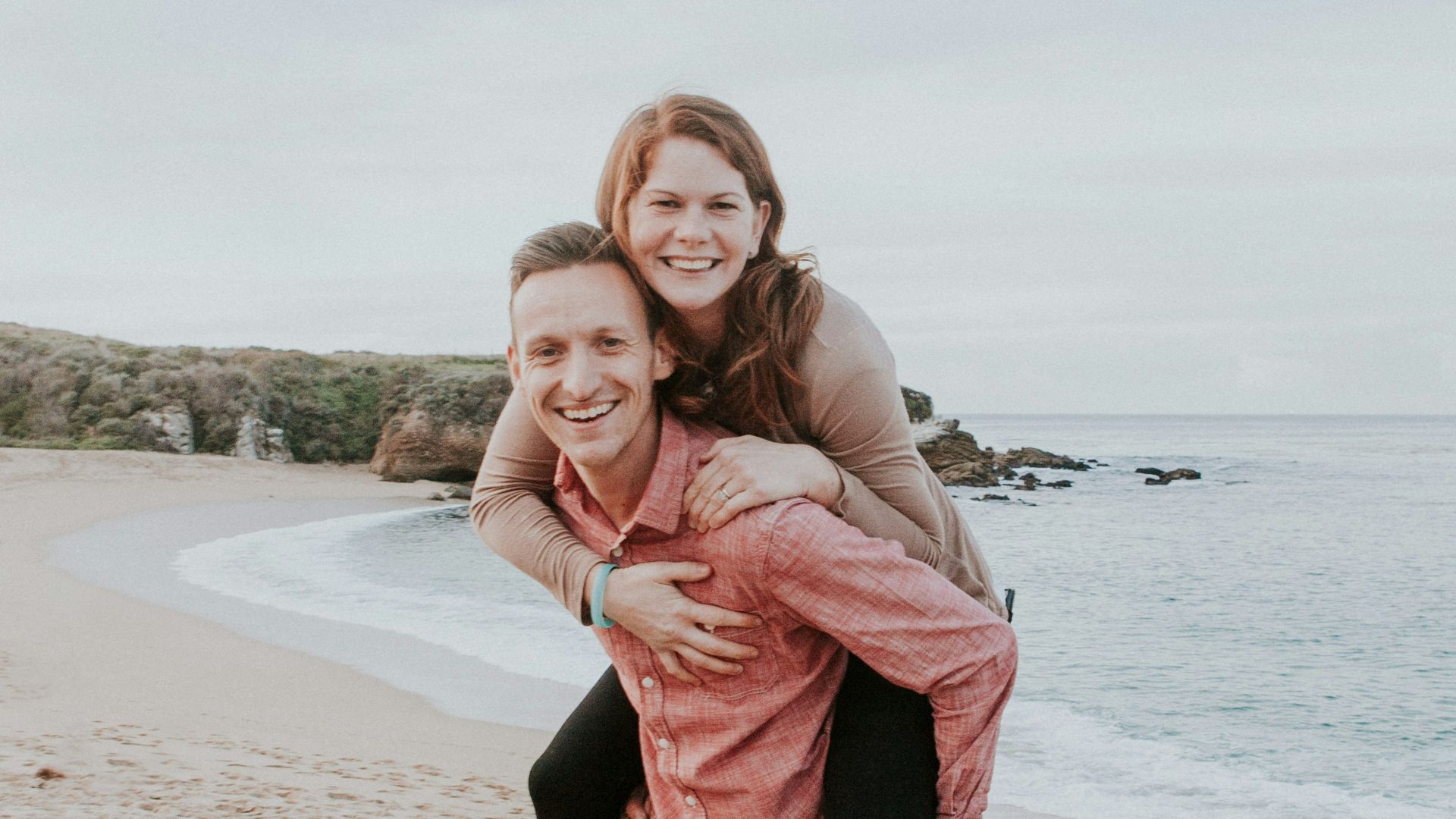 man carrying woman beside seashore