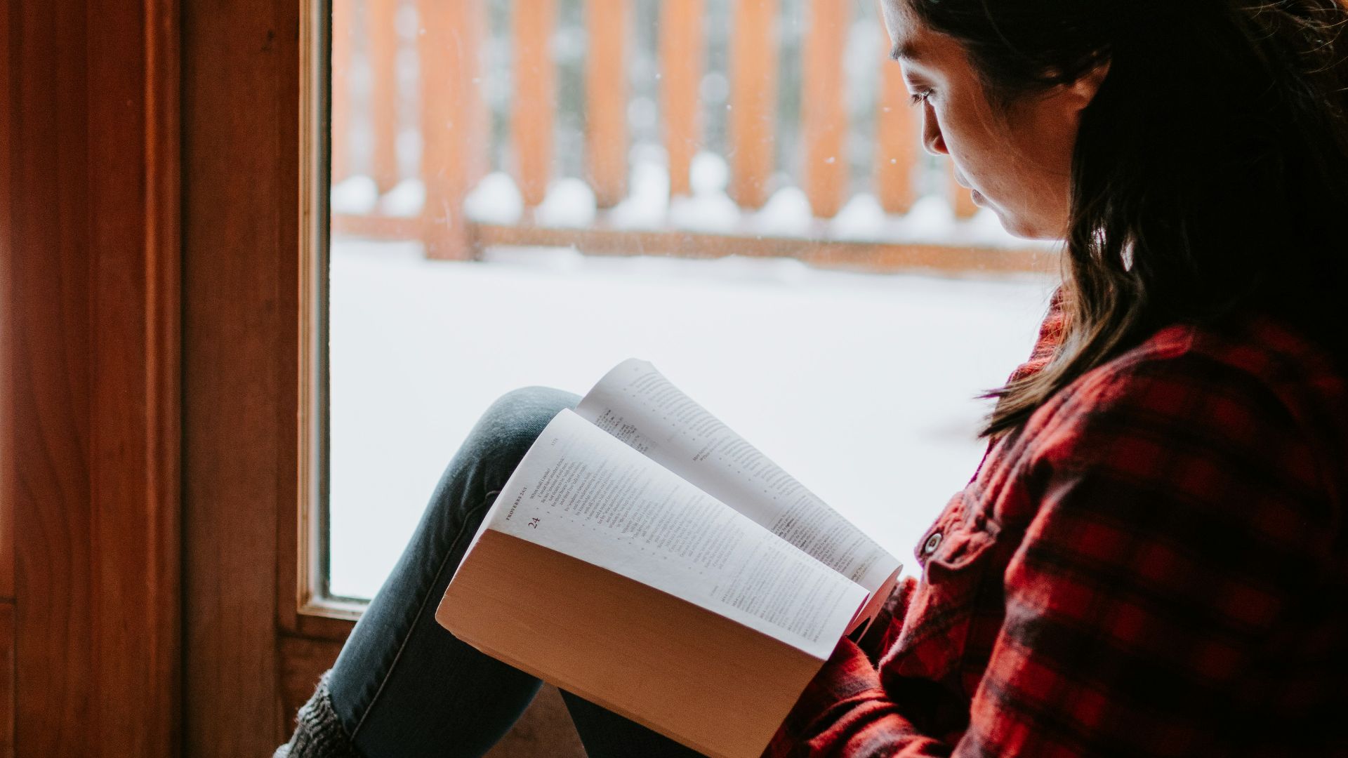 woman in red and black striped long sleeve shirt and blue denim jeans sitting on brown