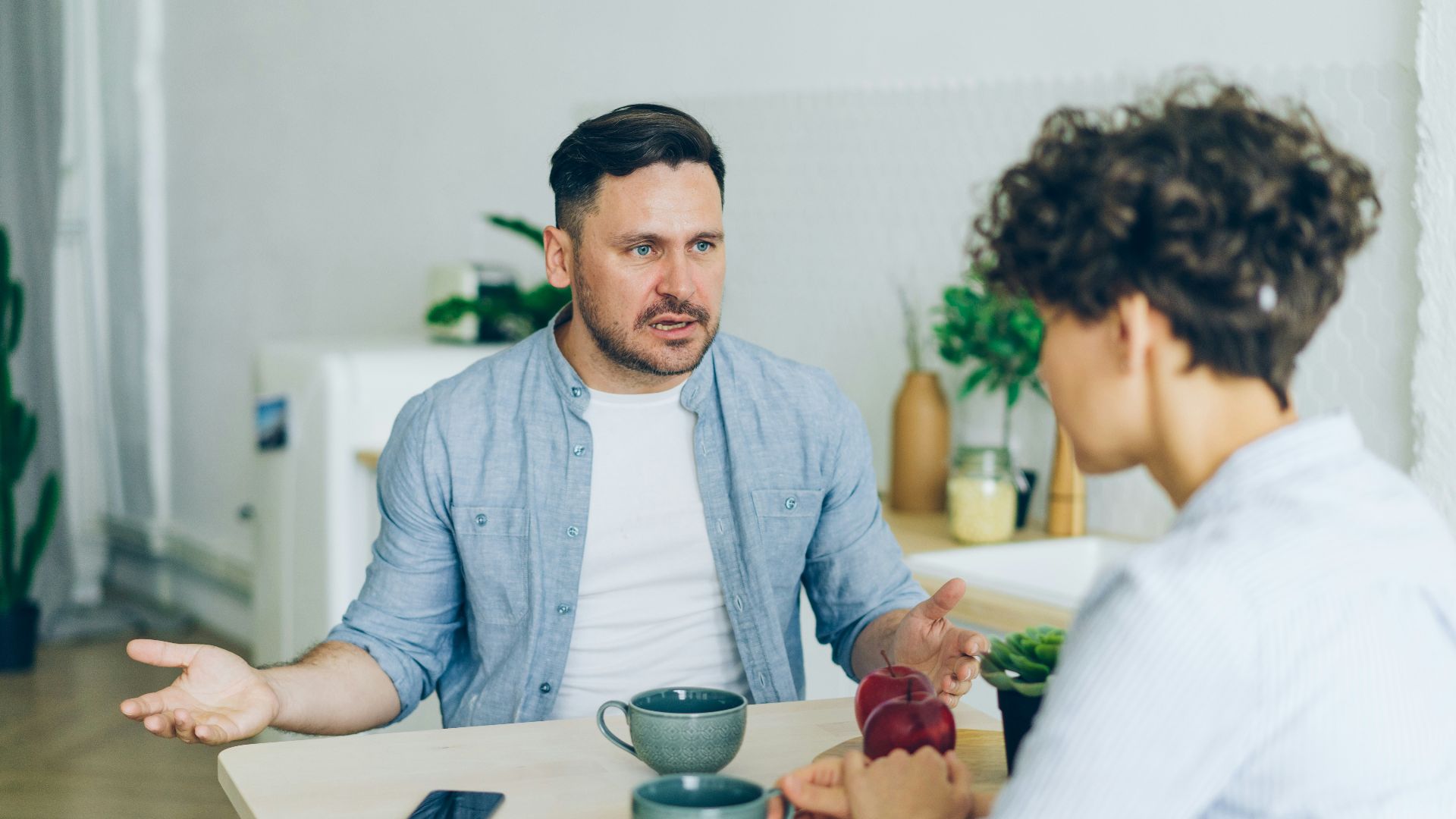 a man sitting at a table talking to a woman