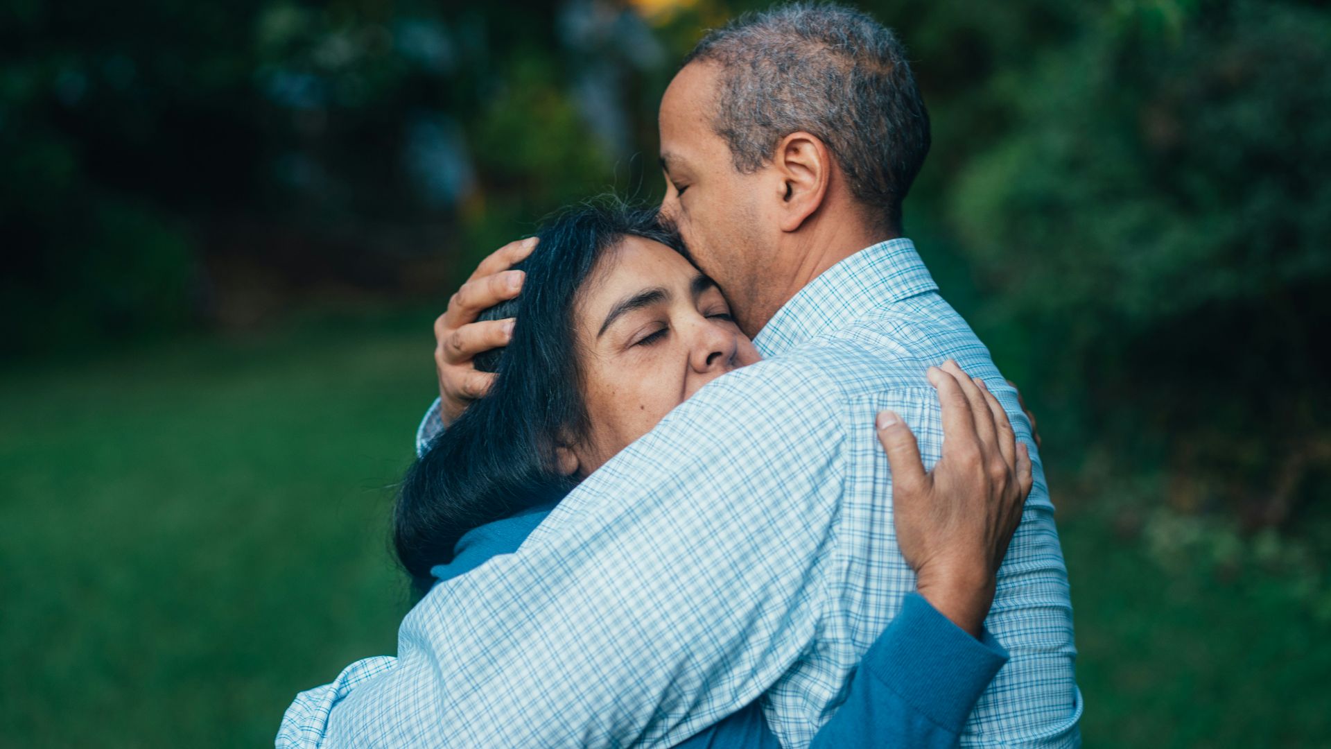 man hugging woman near trees