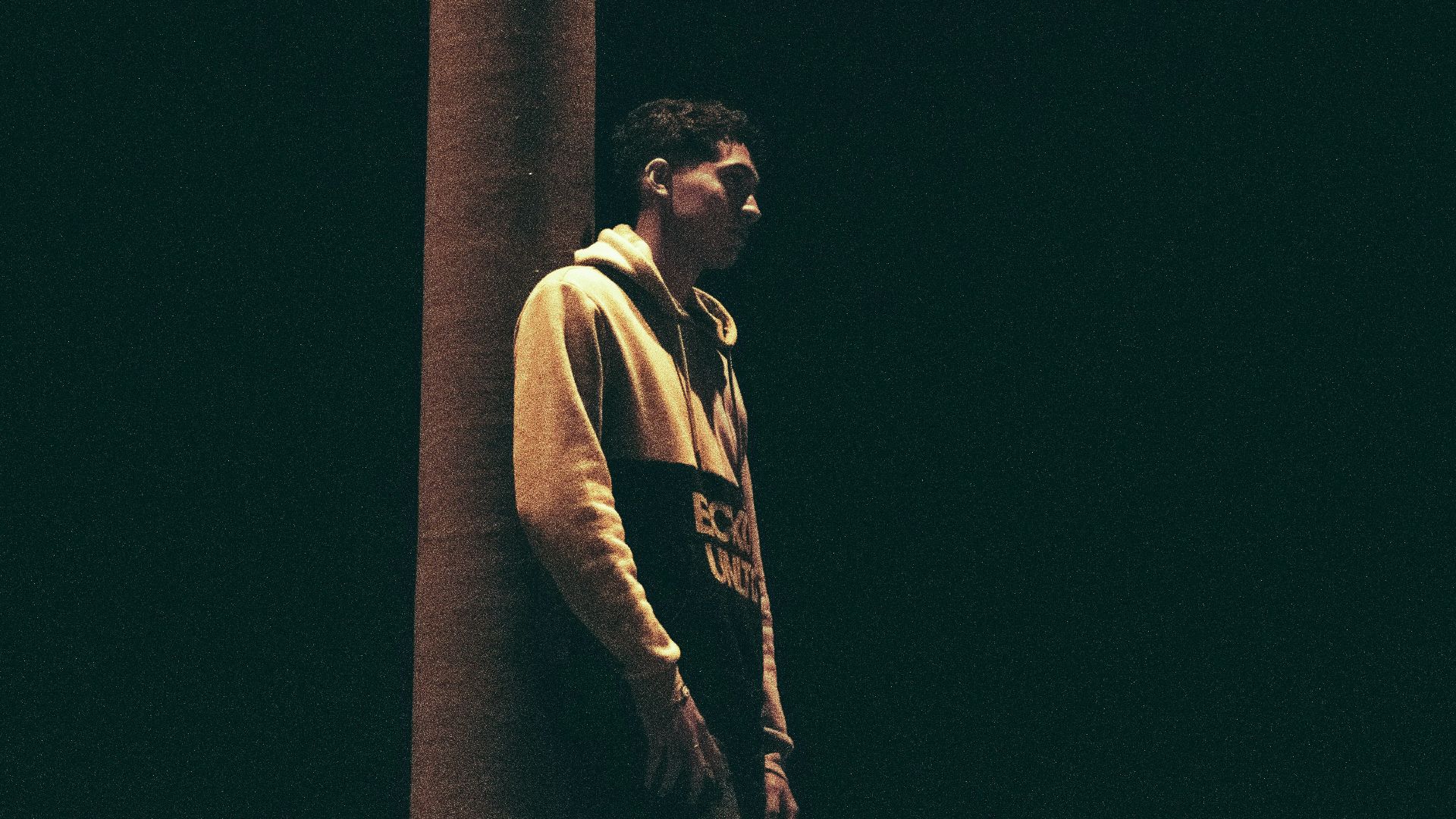 a man leaning against a pillar in the dark