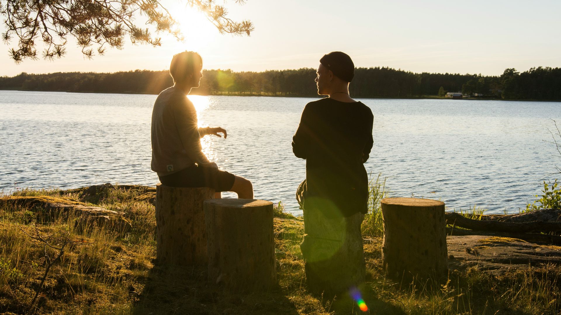 man in black jacket standing beside body of water during sunset