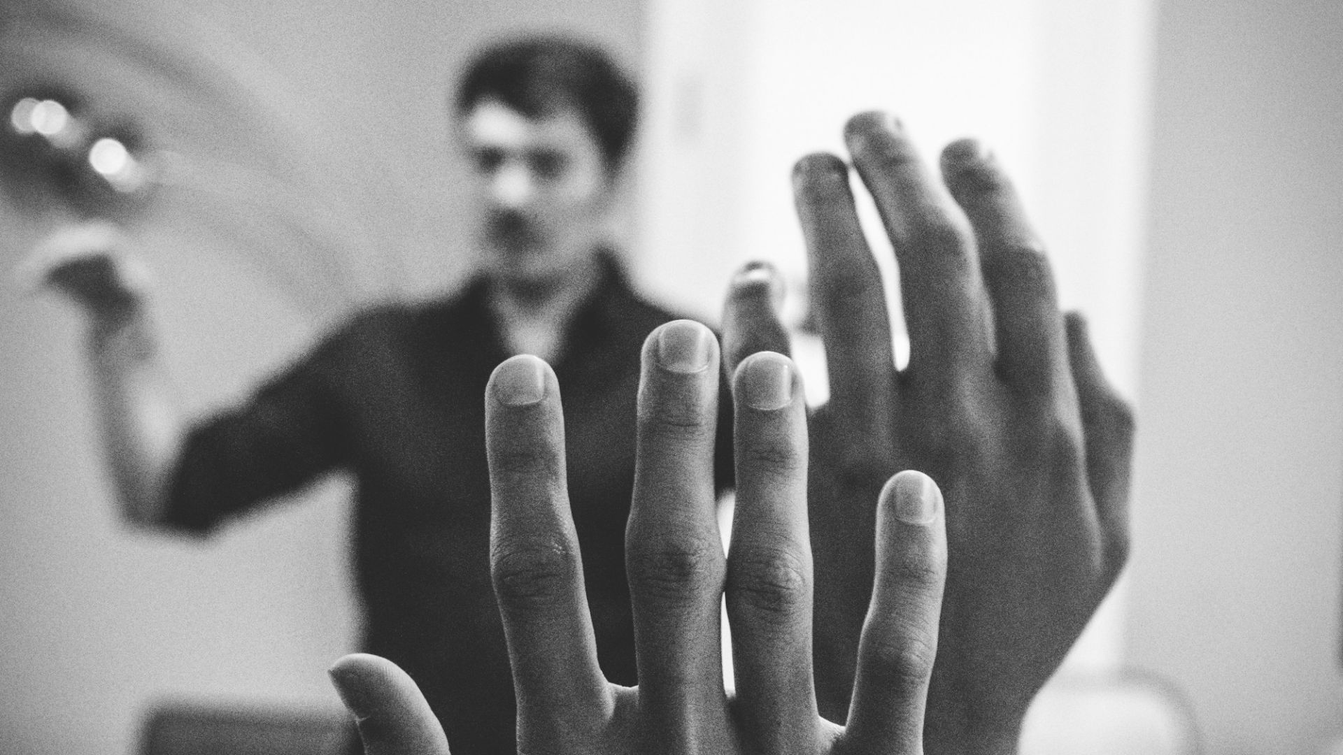 grayscale photography of two people raising their hands