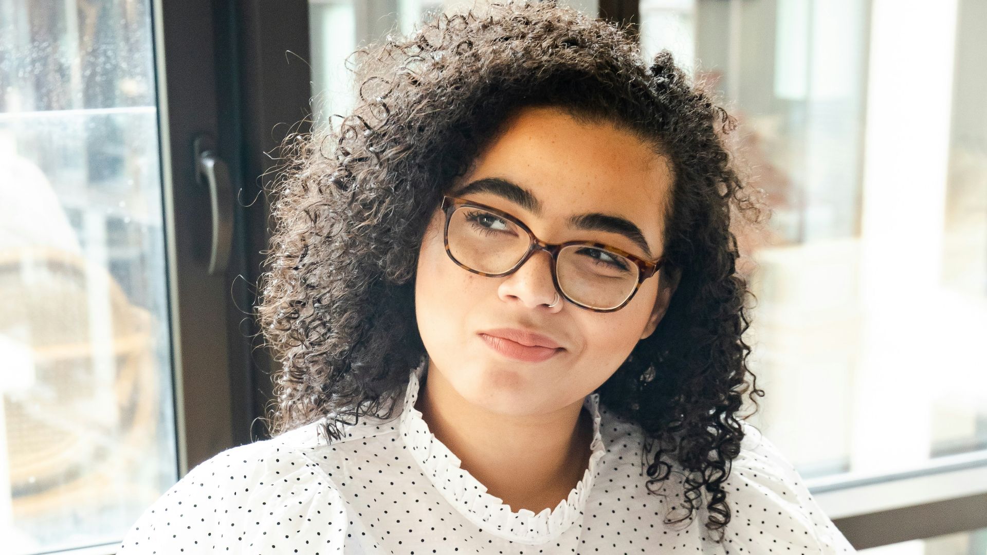 woman in white and black polka dot shirt holding blue and white book