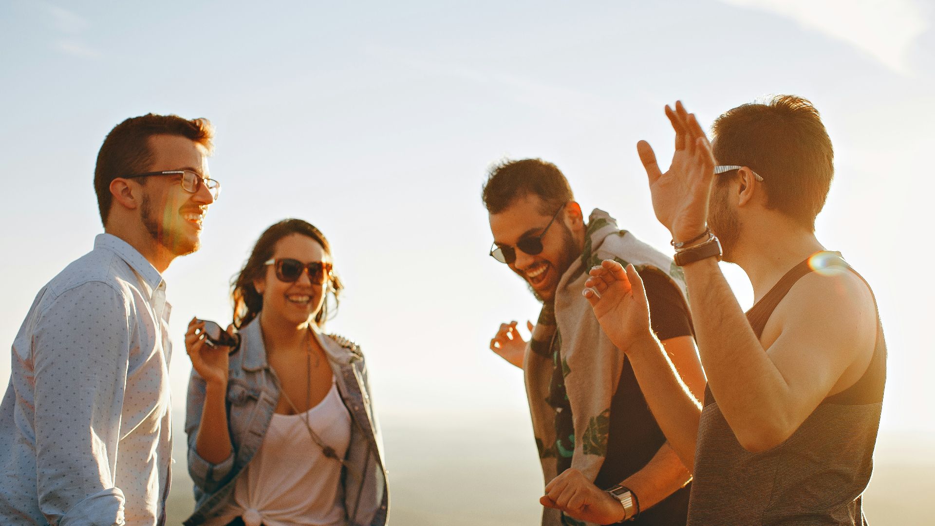 three men and one woman laughing during daytime