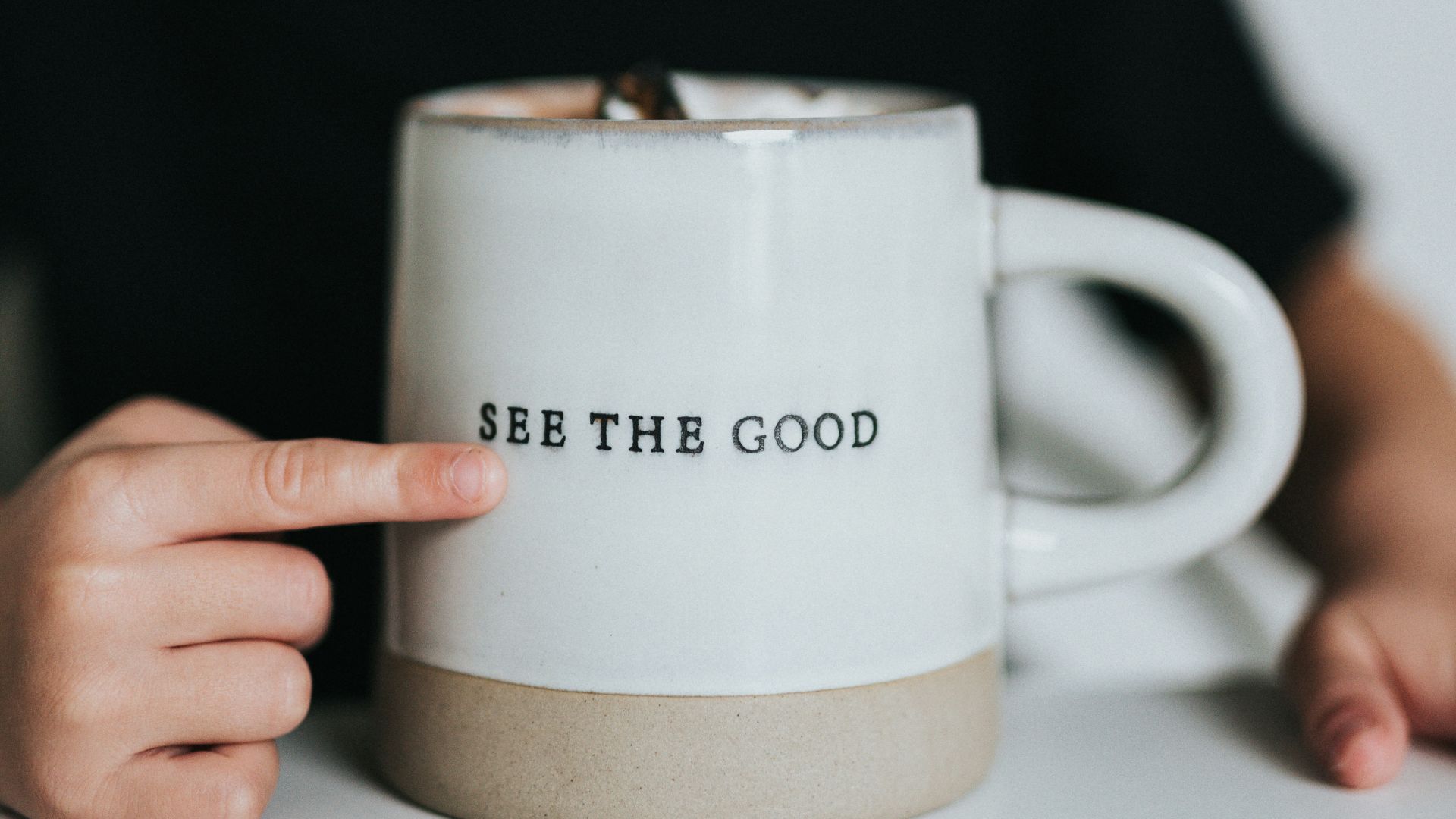 man in black long sleeve shirt holding white ceramic mug