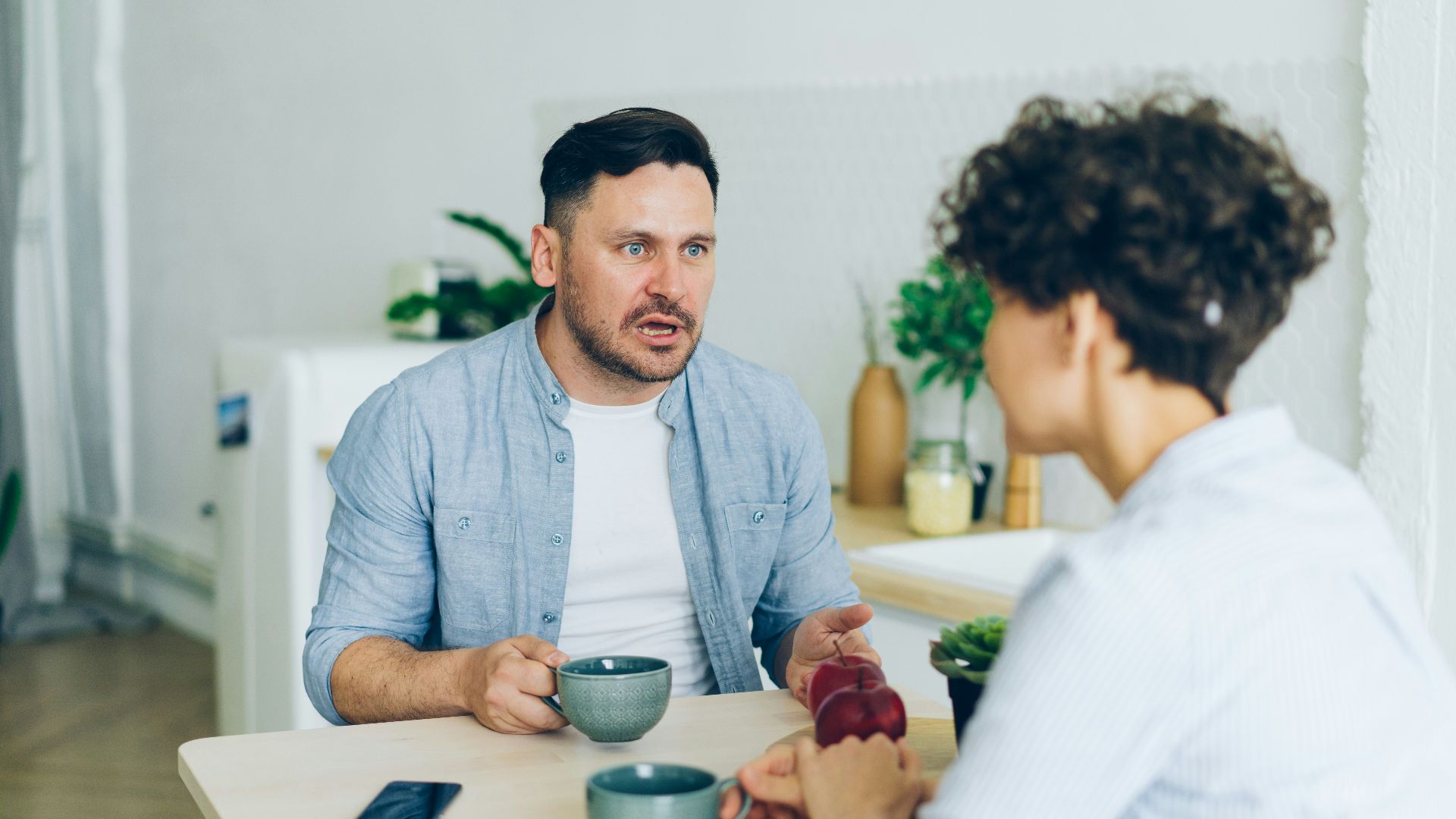 a man sitting at a table talking to a woman