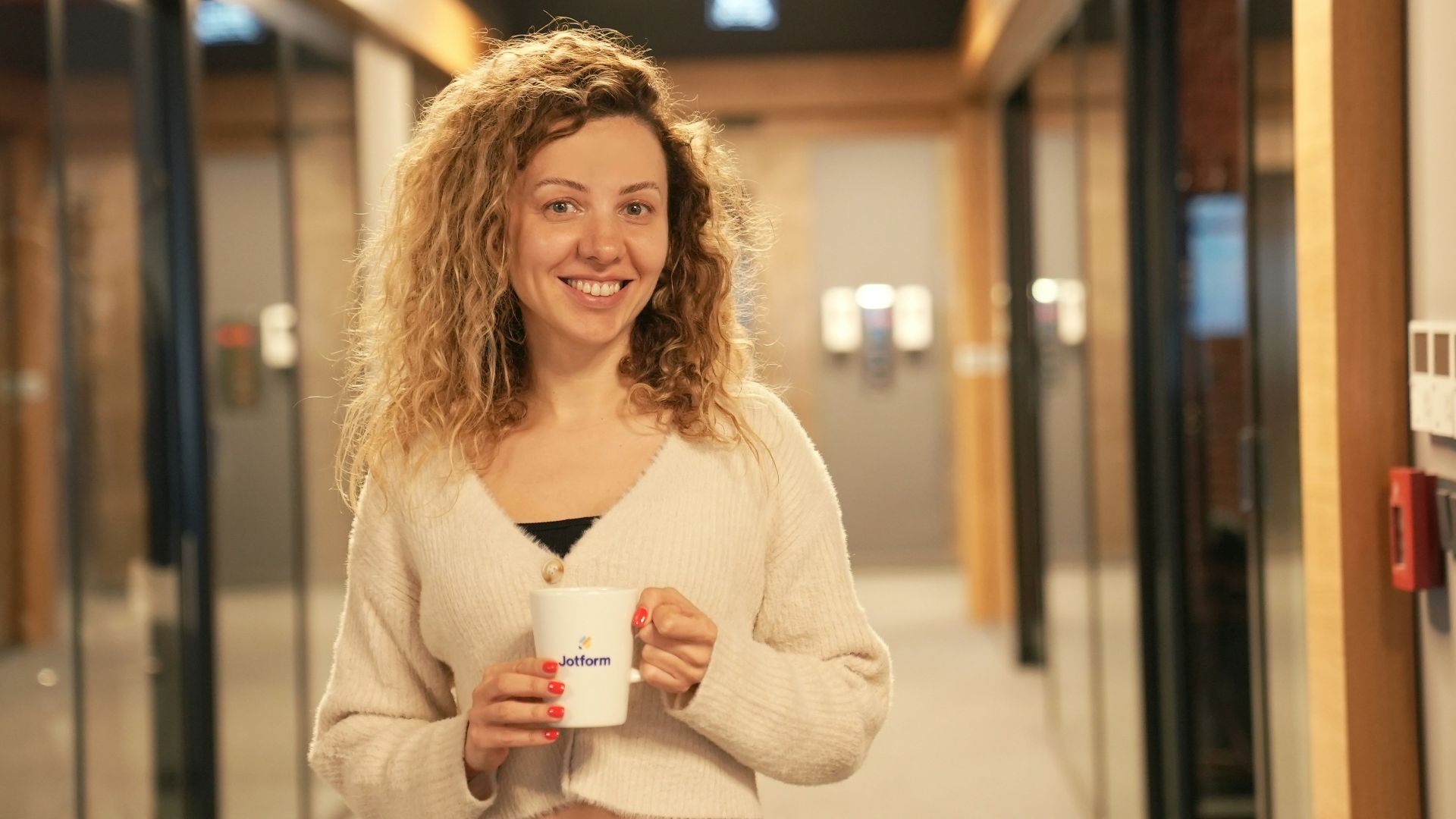 a woman holding a cup of coffee in a hallway
