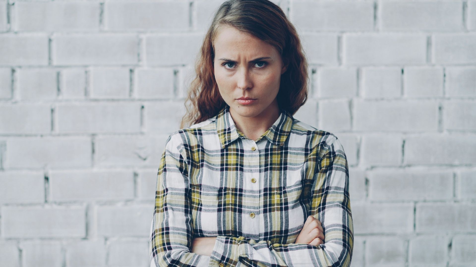 Young woman with arms crossed looks annoyed.