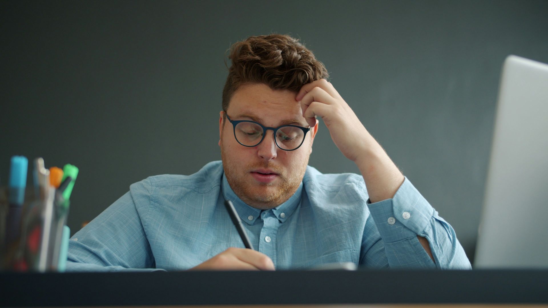 Man with glasses looking stressed at desk