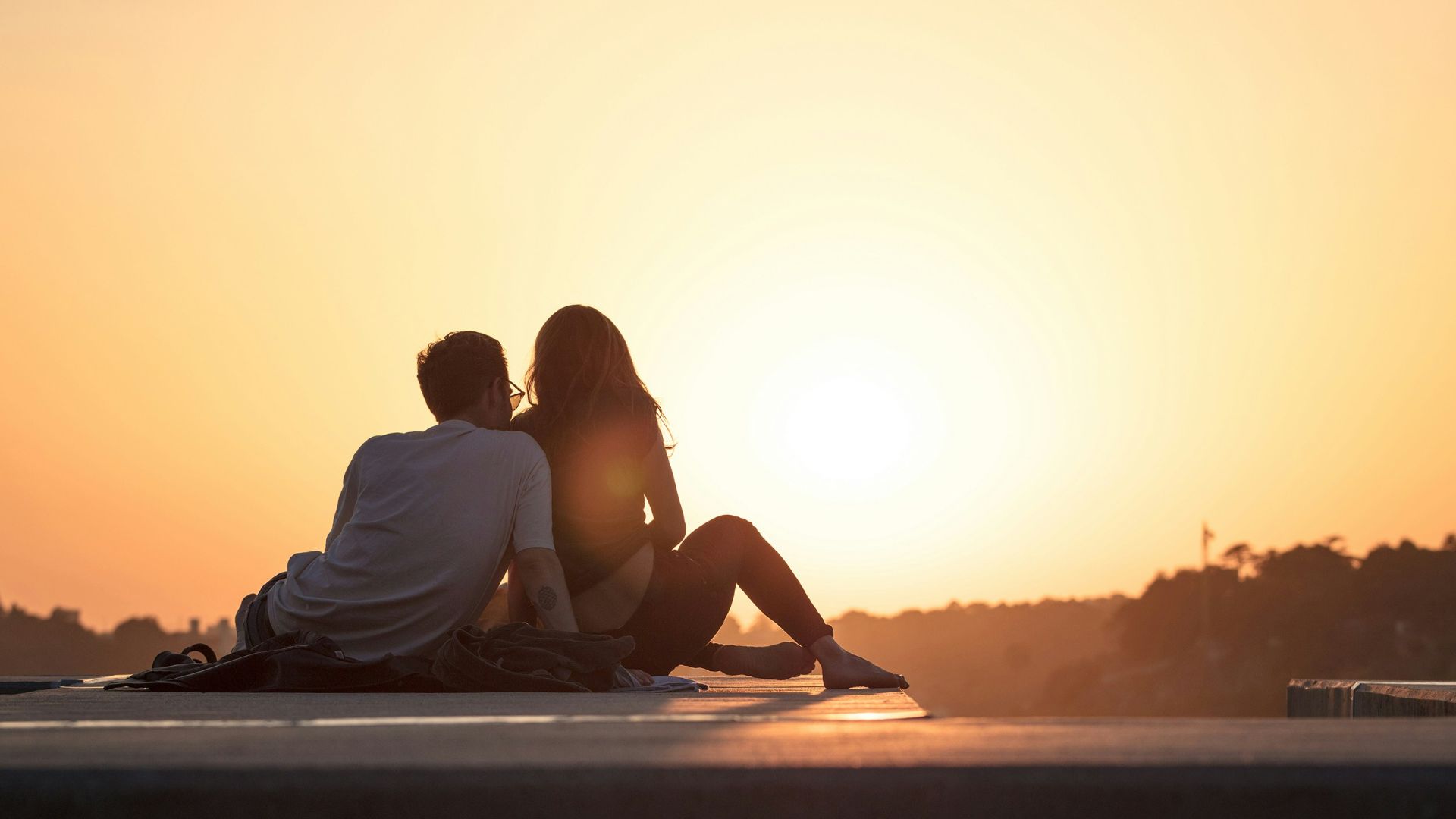 couple sitting near trees during golden hour