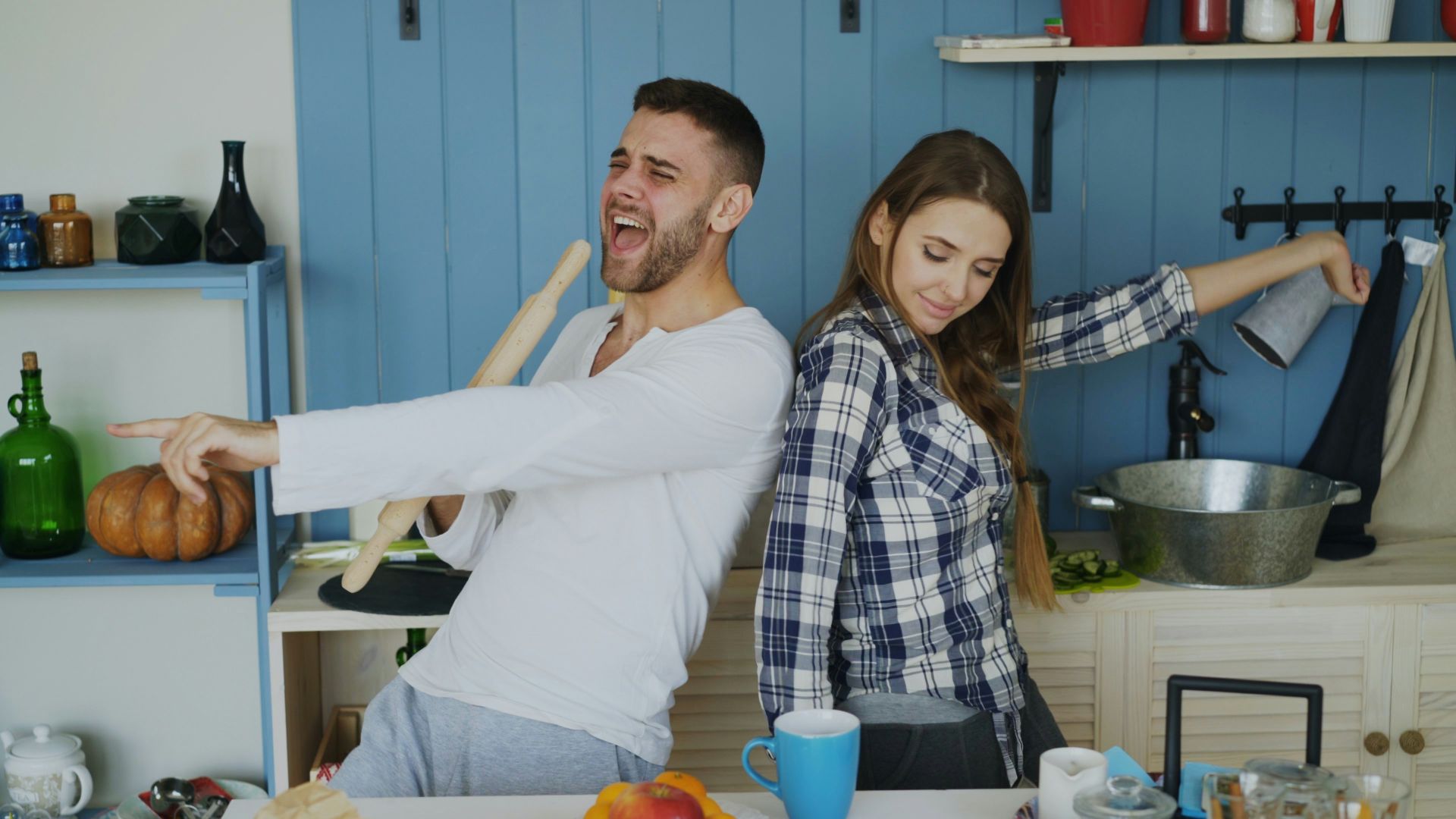 Couple dancing and singing in a kitchen.