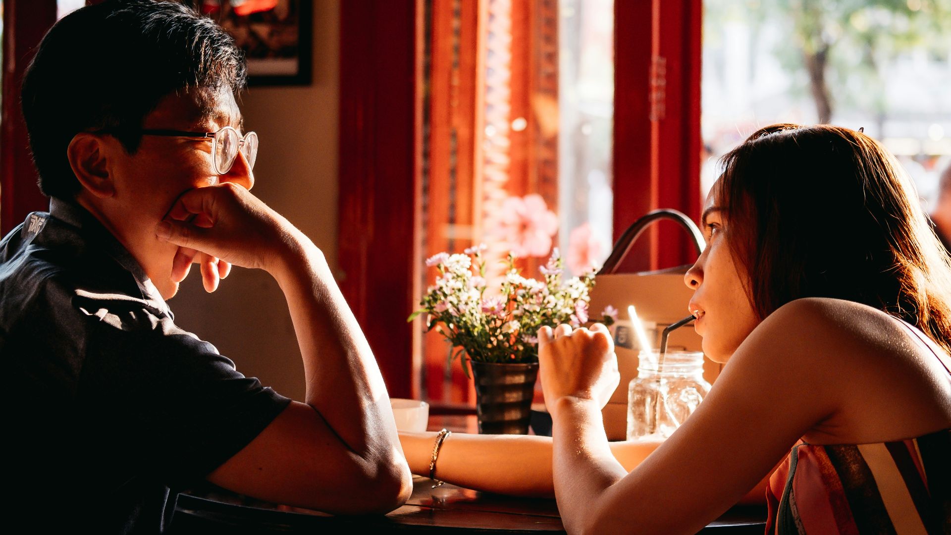 man wearing black collared top sitting on chair in front of table and woman wearing multicolored top