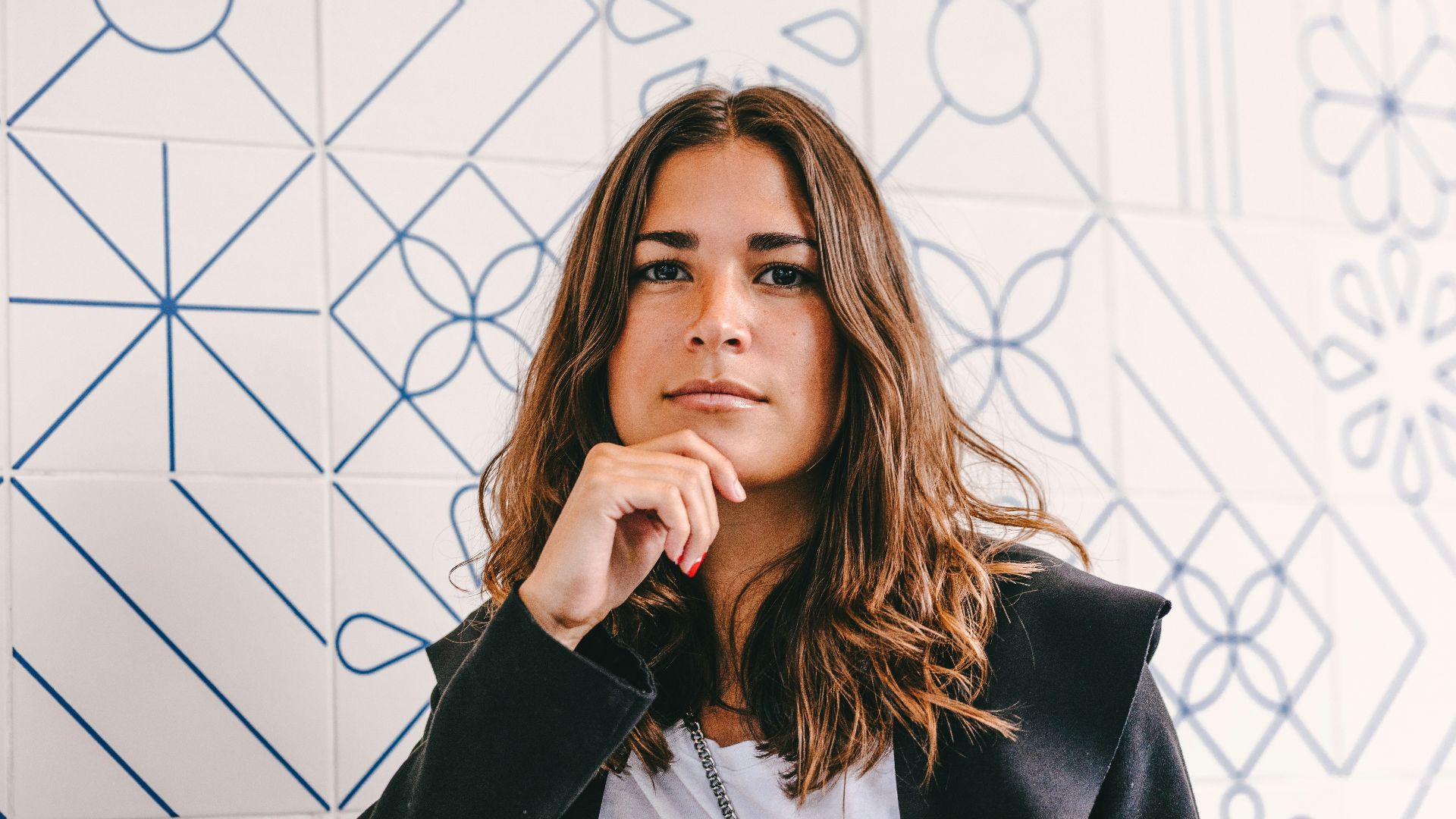 woman in black blazer covering her face with her hand