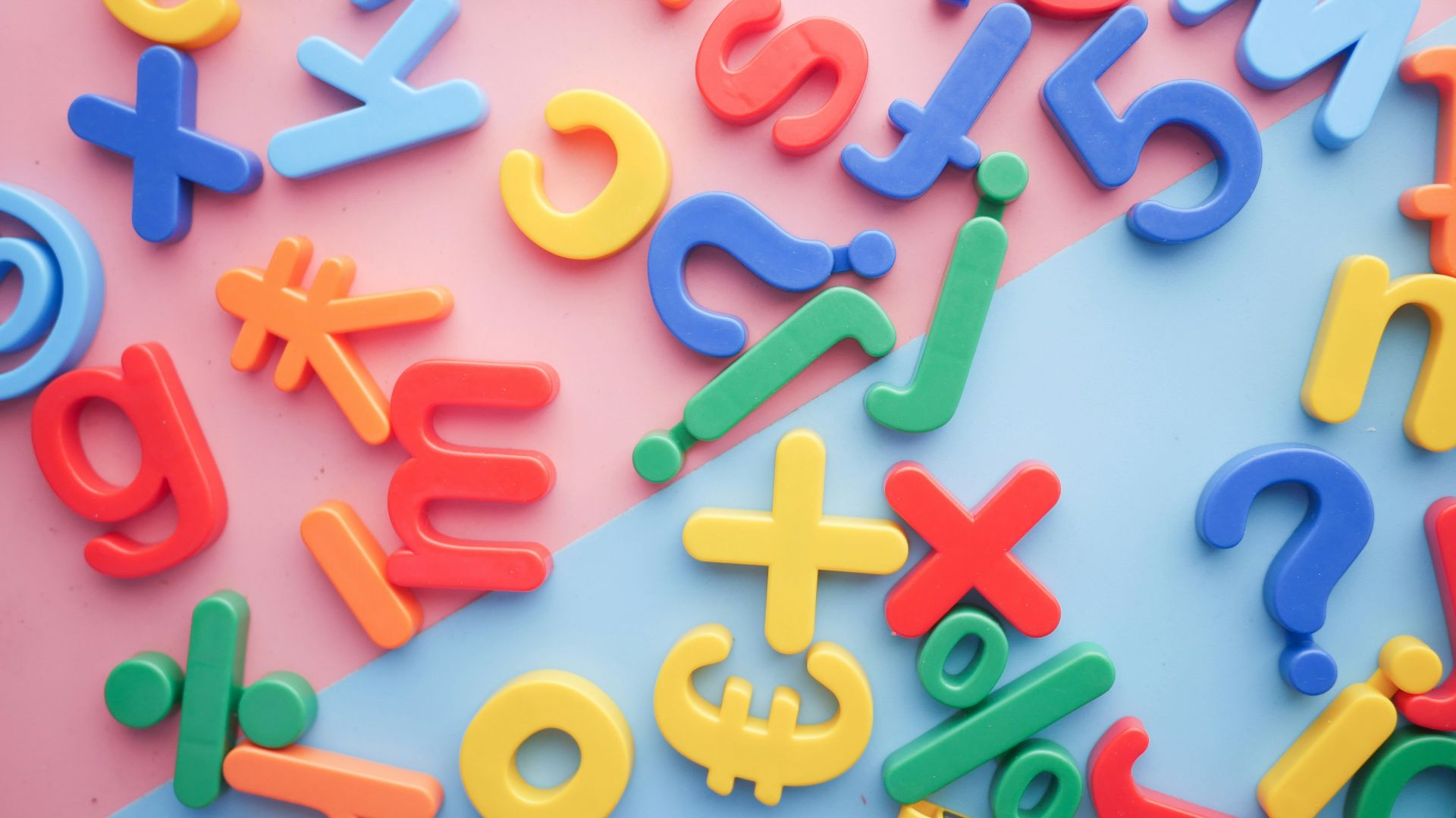 a pile of plastic letters and numbers on a pink and blue background