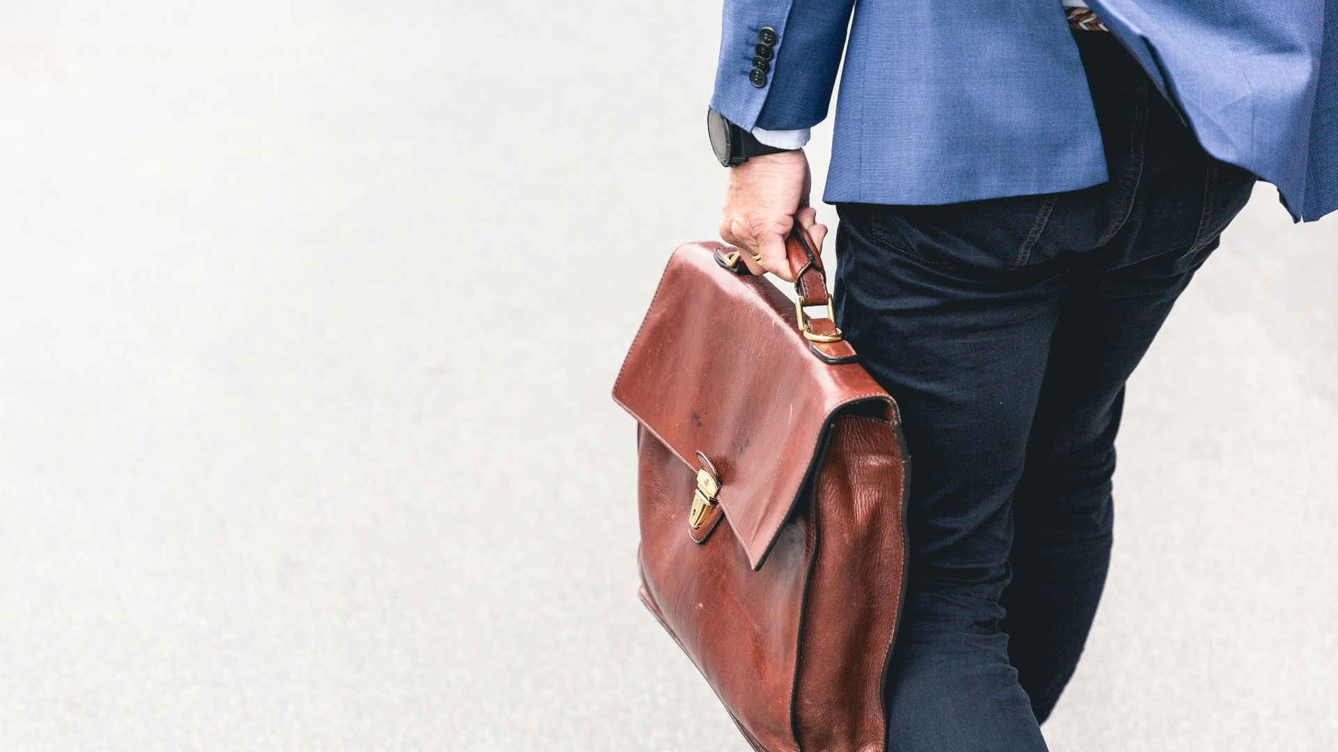 person walking holding brown leather bag