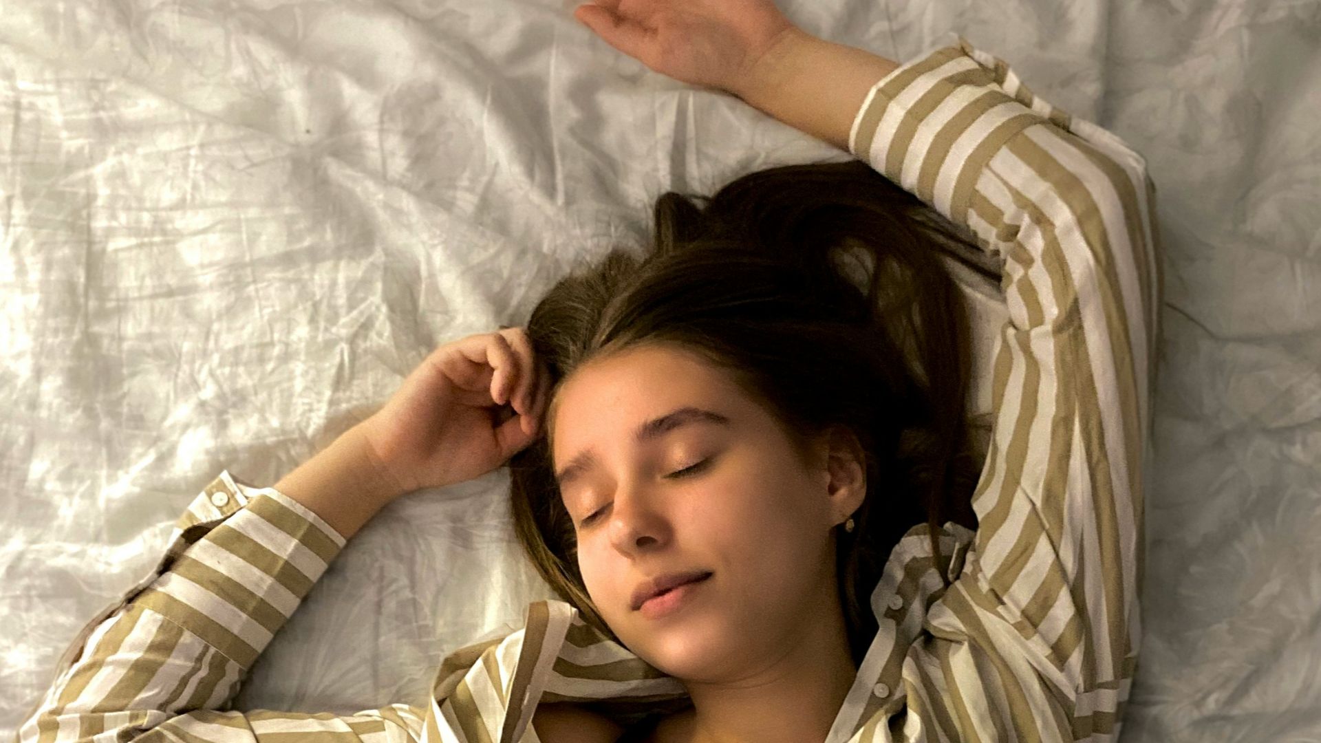 woman in white and black striped long sleeve shirt lying on bed