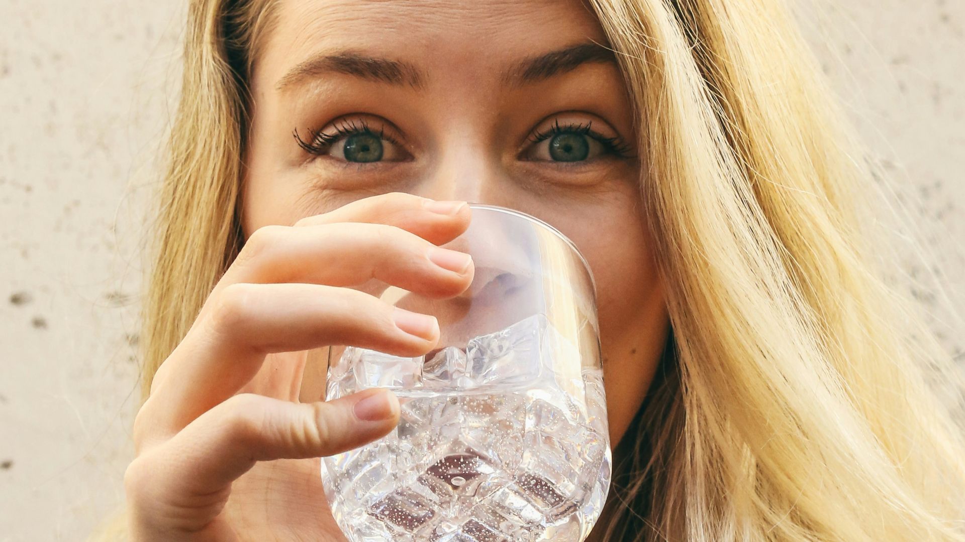 woman in white crew neck shirt drinking water
