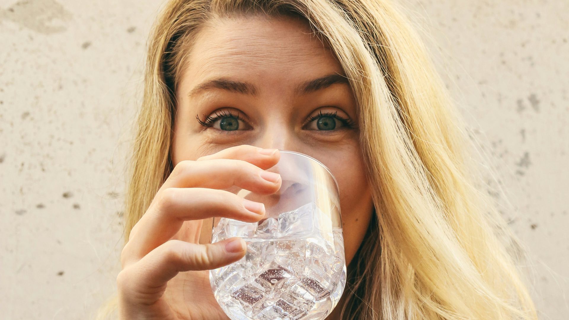 woman in white crew neck shirt drinking water