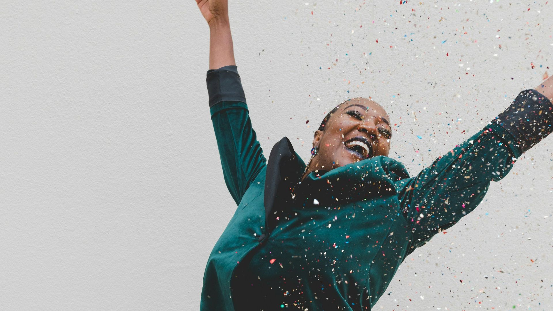 woman in green jacket raising her hands