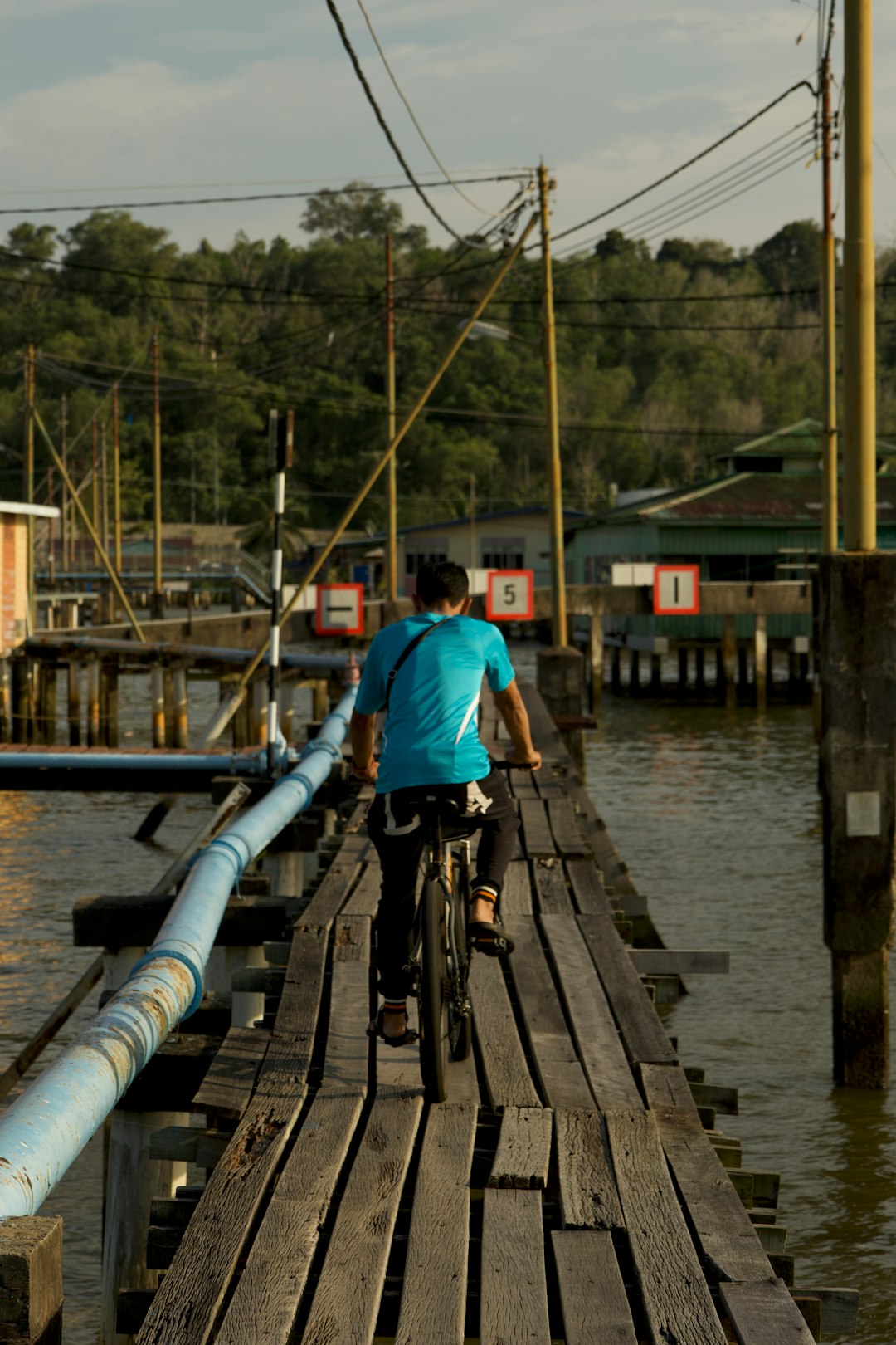 a man riding a bike across a wooden bridge