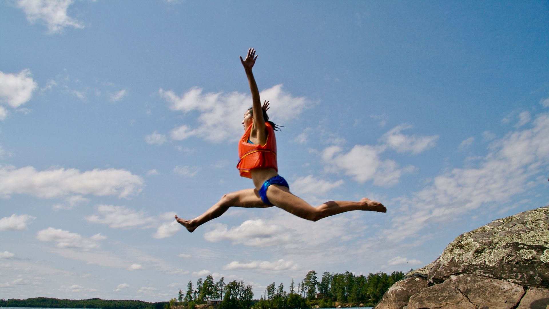 woman jumping towards water wearing life vest