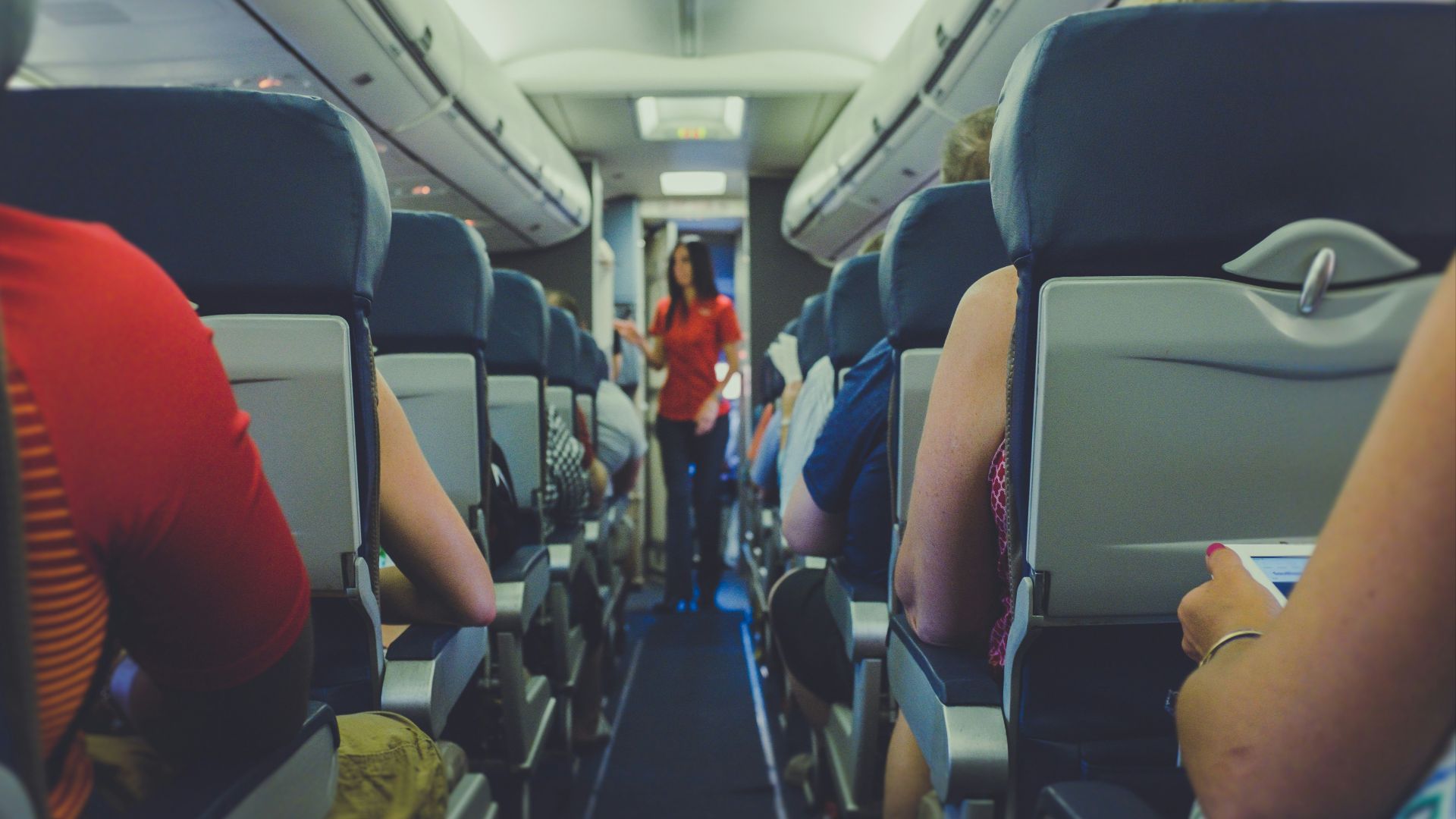 flight attendant standing between passenger seat