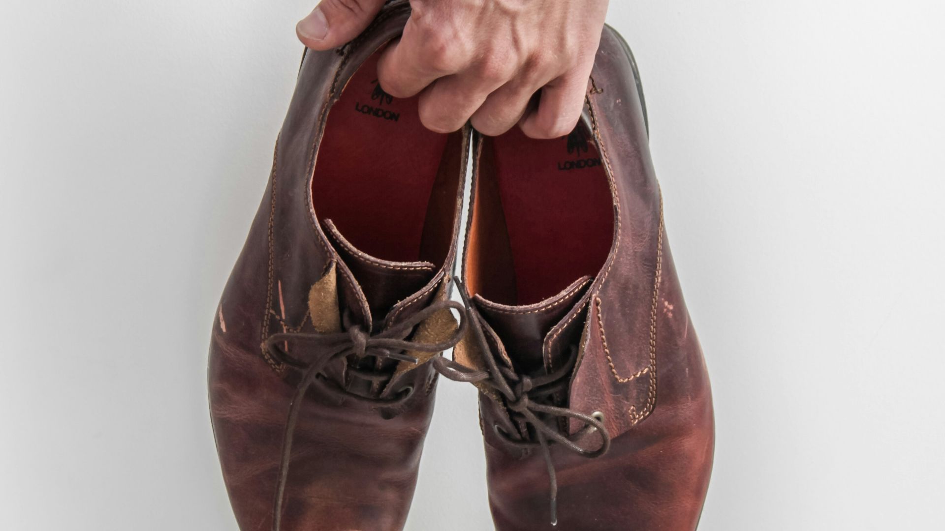 person holding pair of brown leather shoes