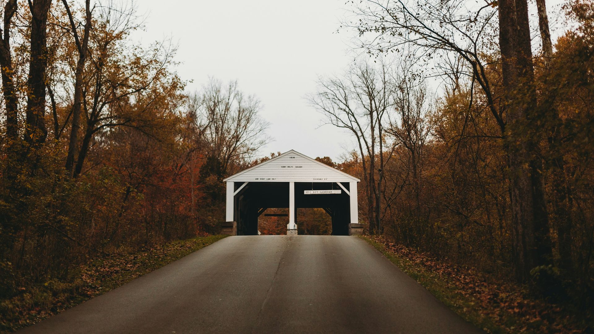 a covered bridge in the middle of a wooded area
