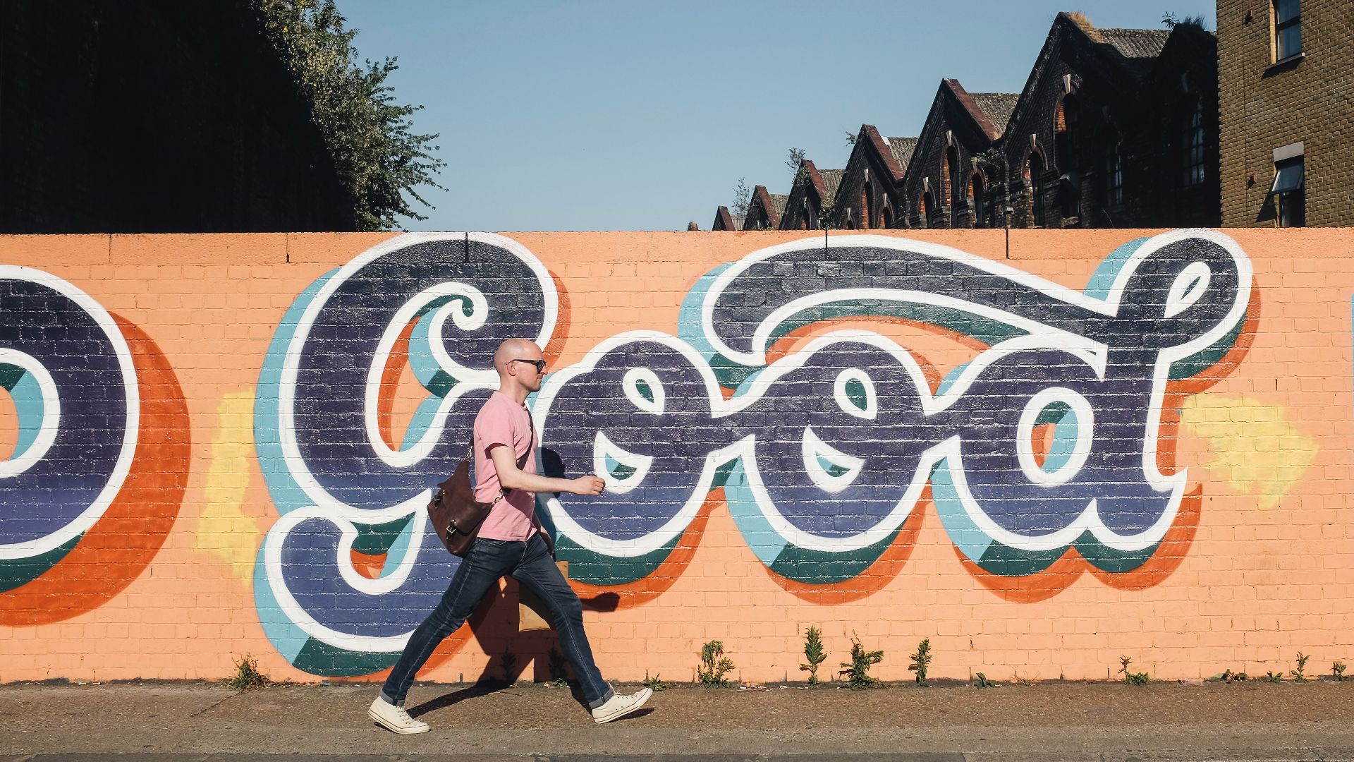 man walking beside graffiti wall