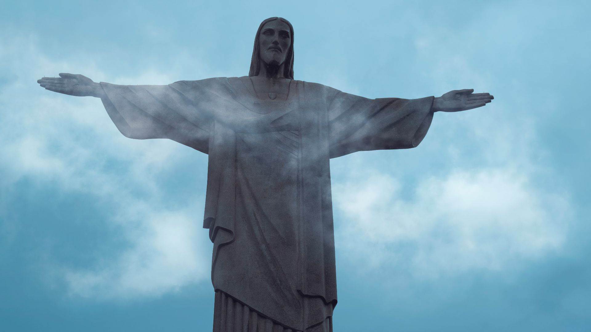 a statue of a person holding the arms out with Christ the Redeemer in the background