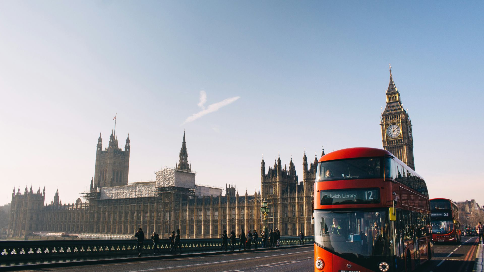 red double-decker bus passing Palace of Westminster, London during daytime