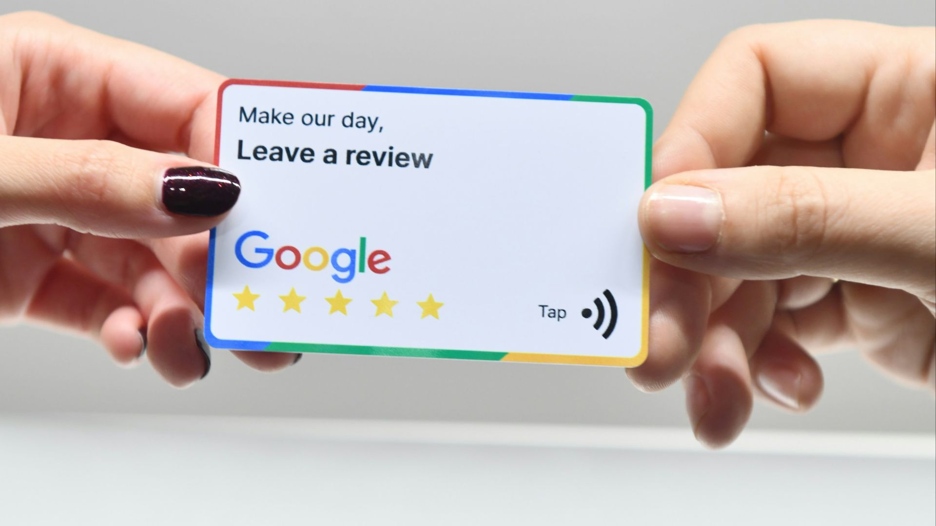 two hands holding a google credit card in front of an apple logo