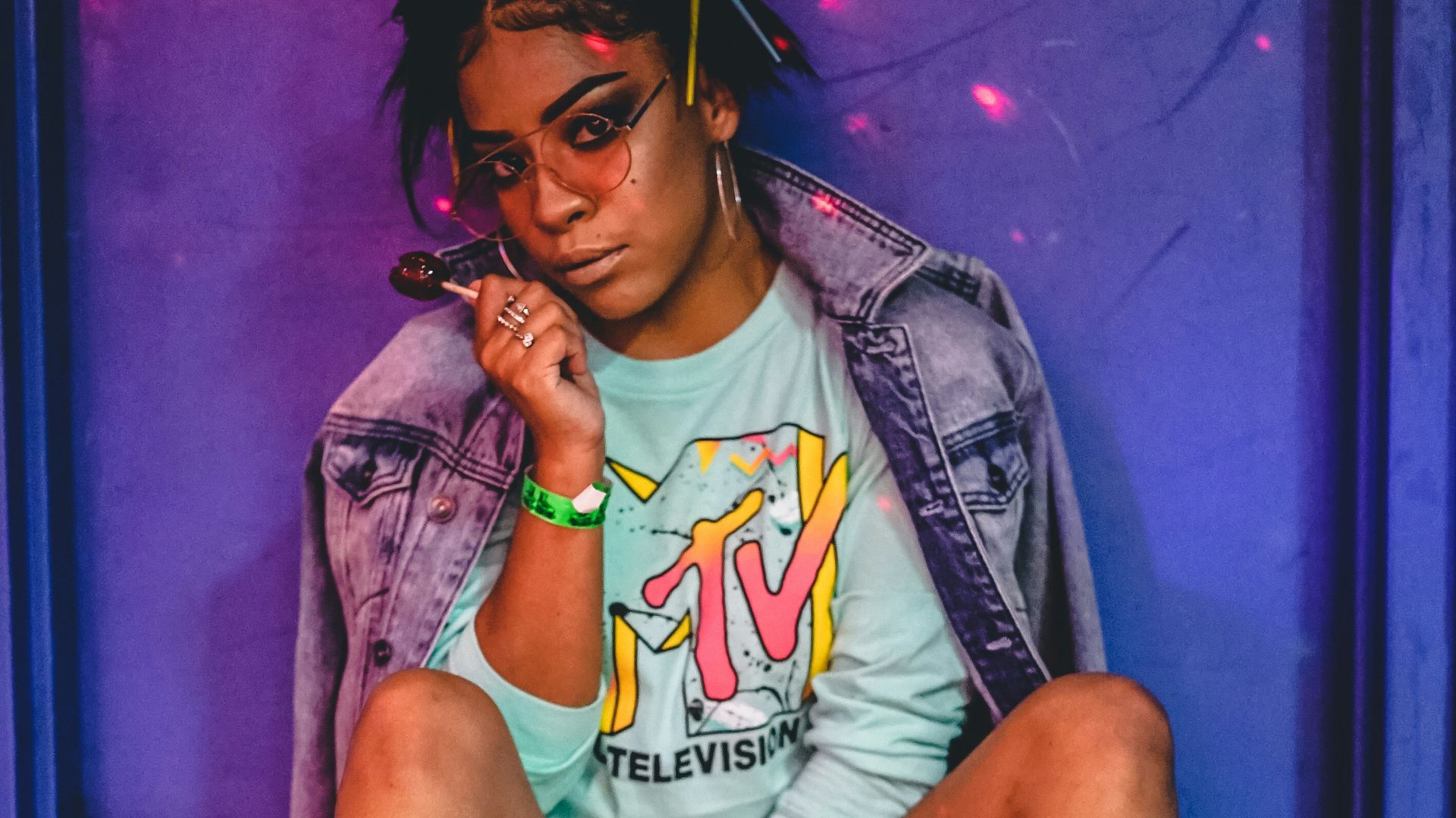 woman sitting wearing roller skates and jacket while holding lollipop