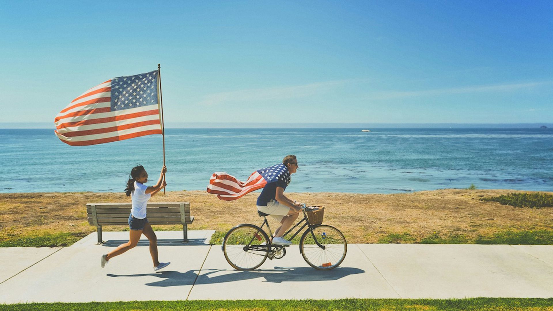 man riding bike and woman running holding flag of USA