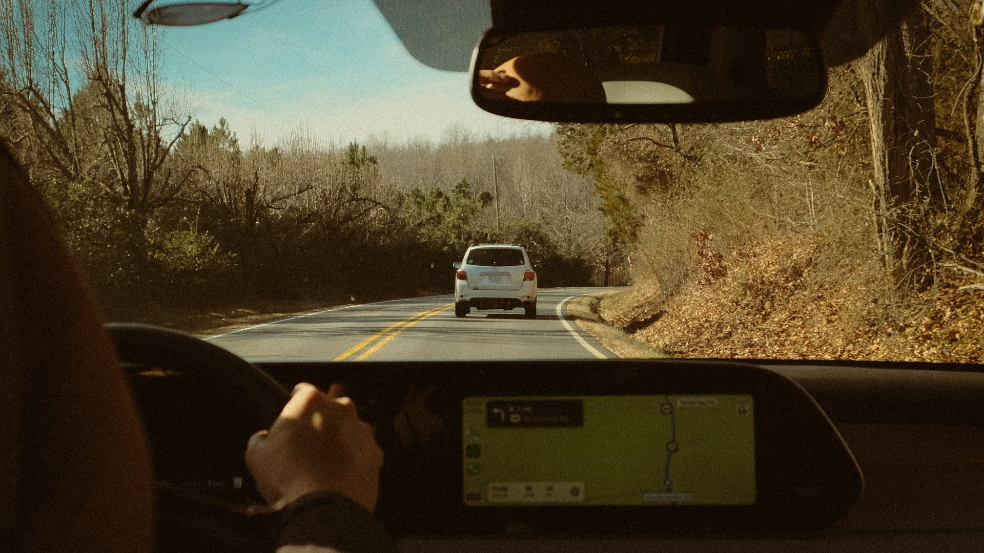 a person driving a car on a road next to a forest