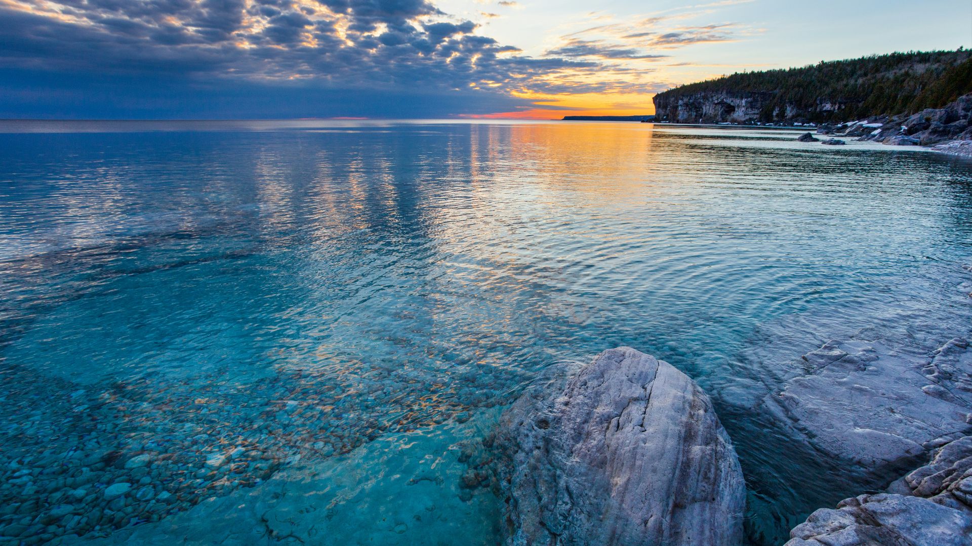 a large body of water with rocks in the foreground