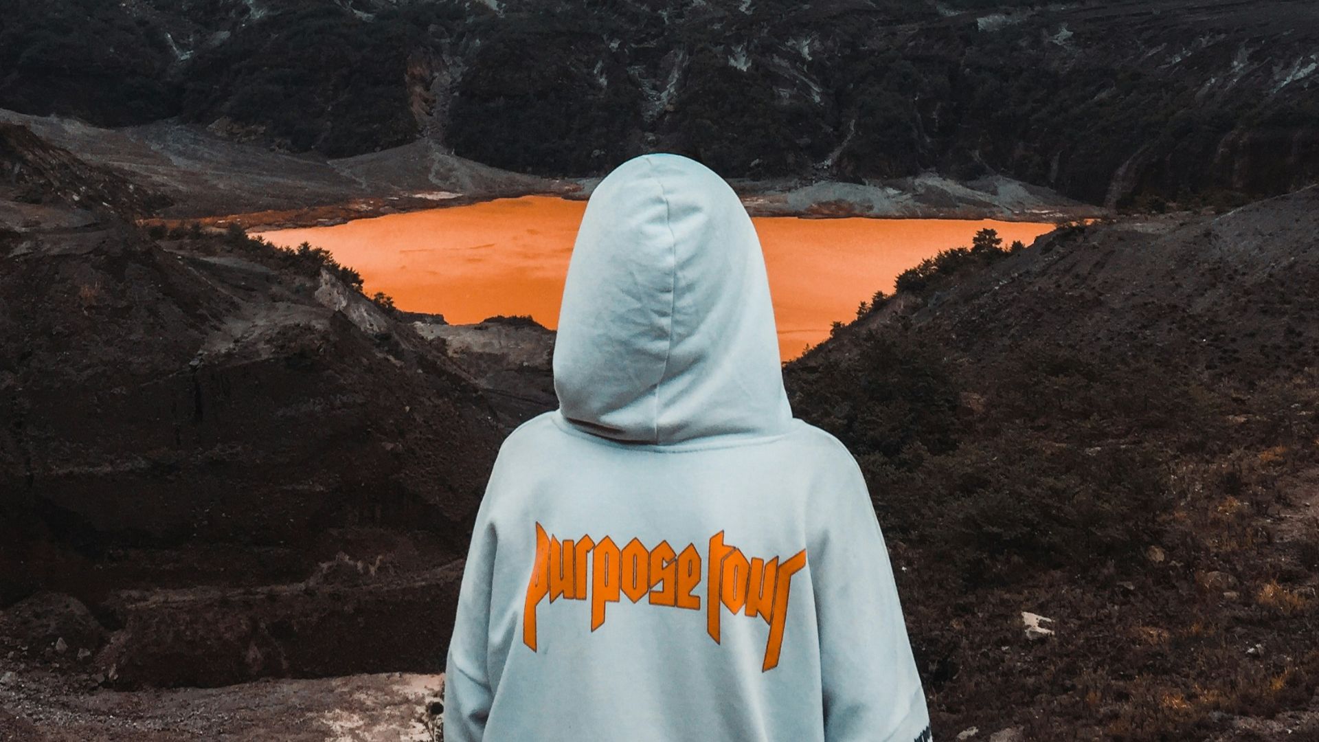 person wearing hoodie facing body of water