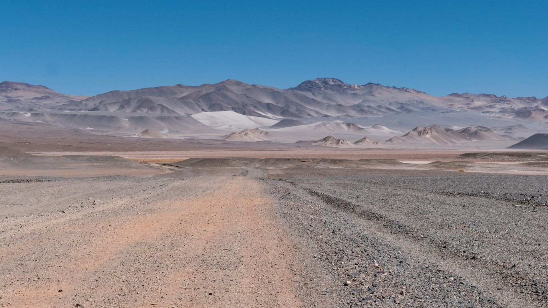 a dirt road with mountains in the background