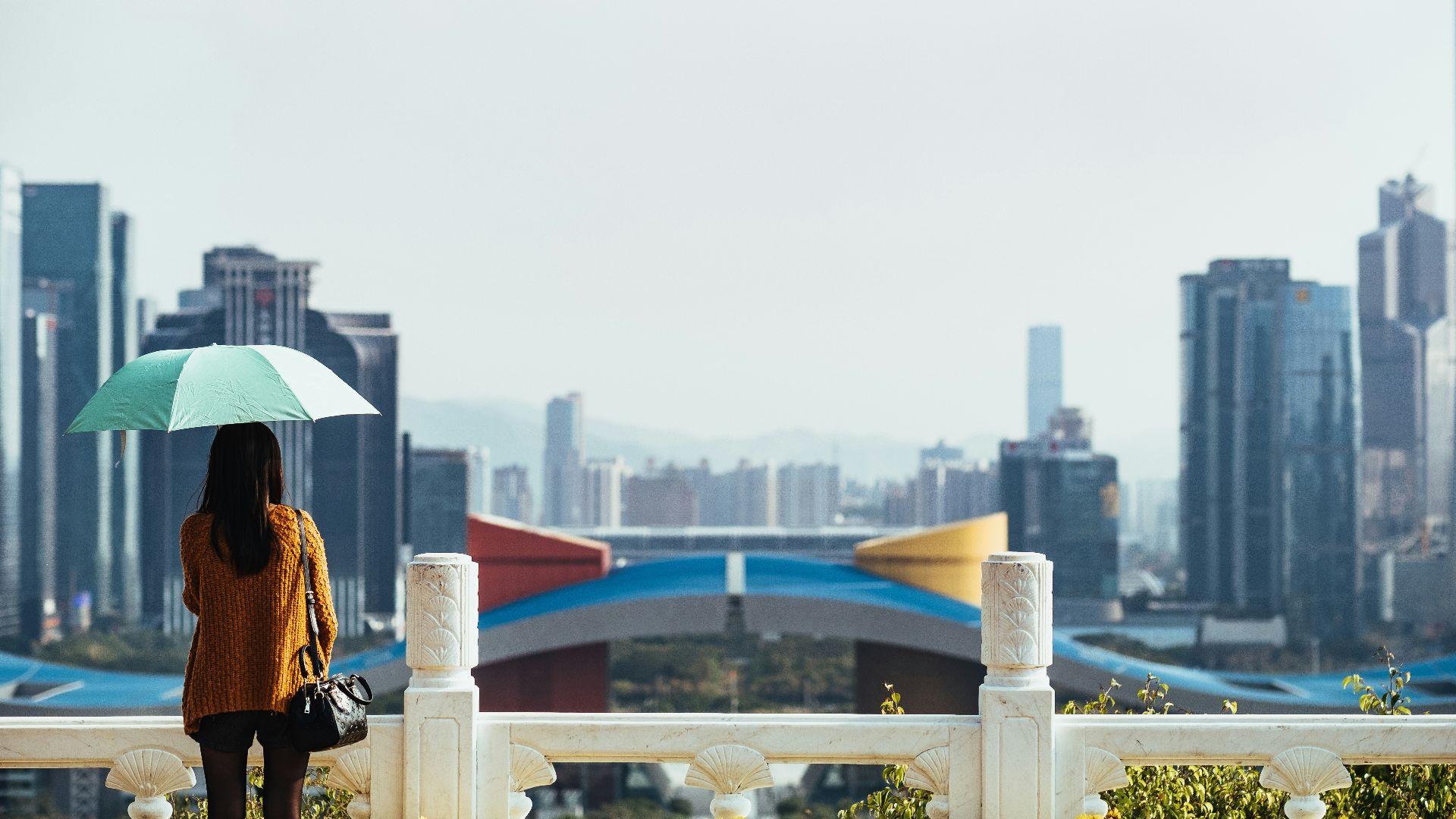 woman using blue umbrella standing in front of fence
