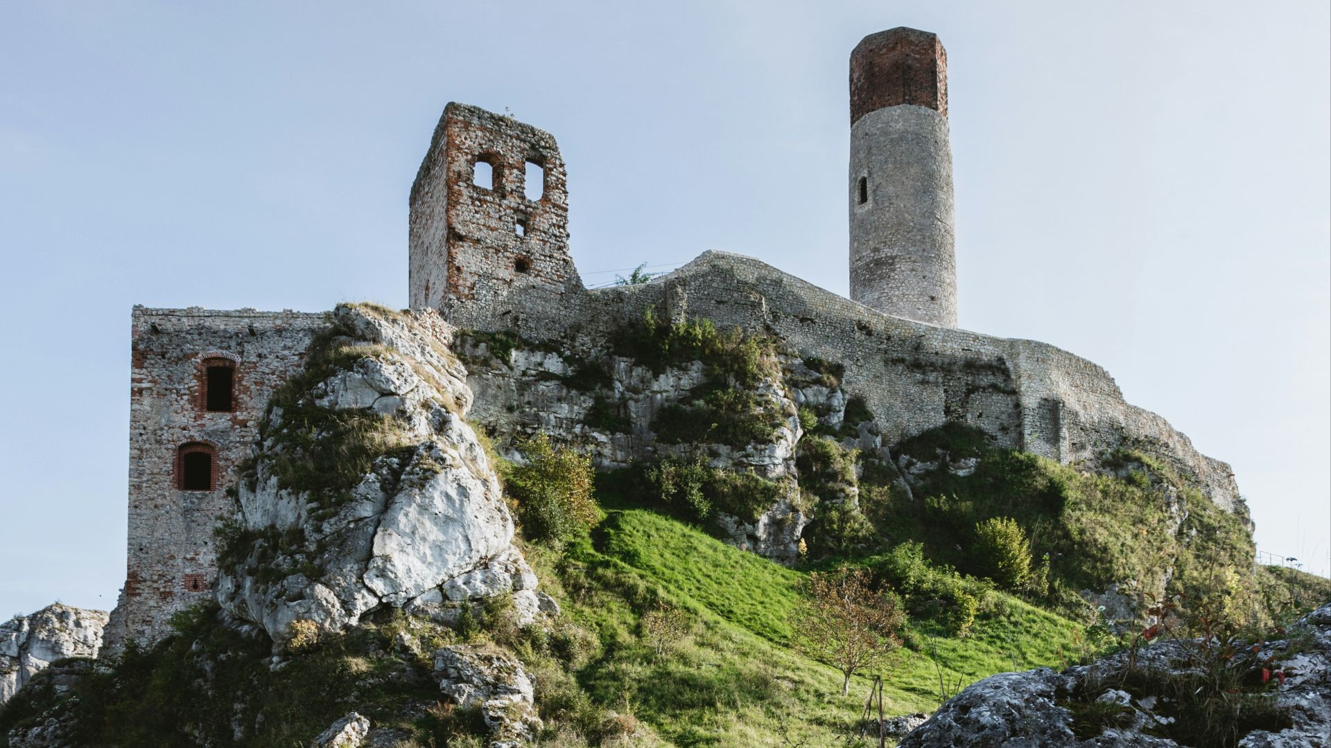 a stone castle on a hill with Ogrodzieniec Castle in the background