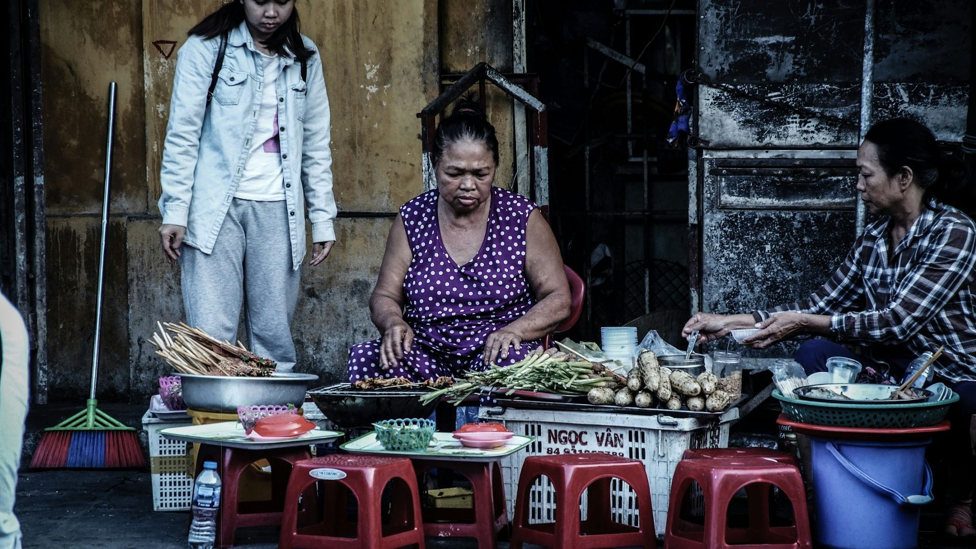 woman sitting in front vegetables beside two women